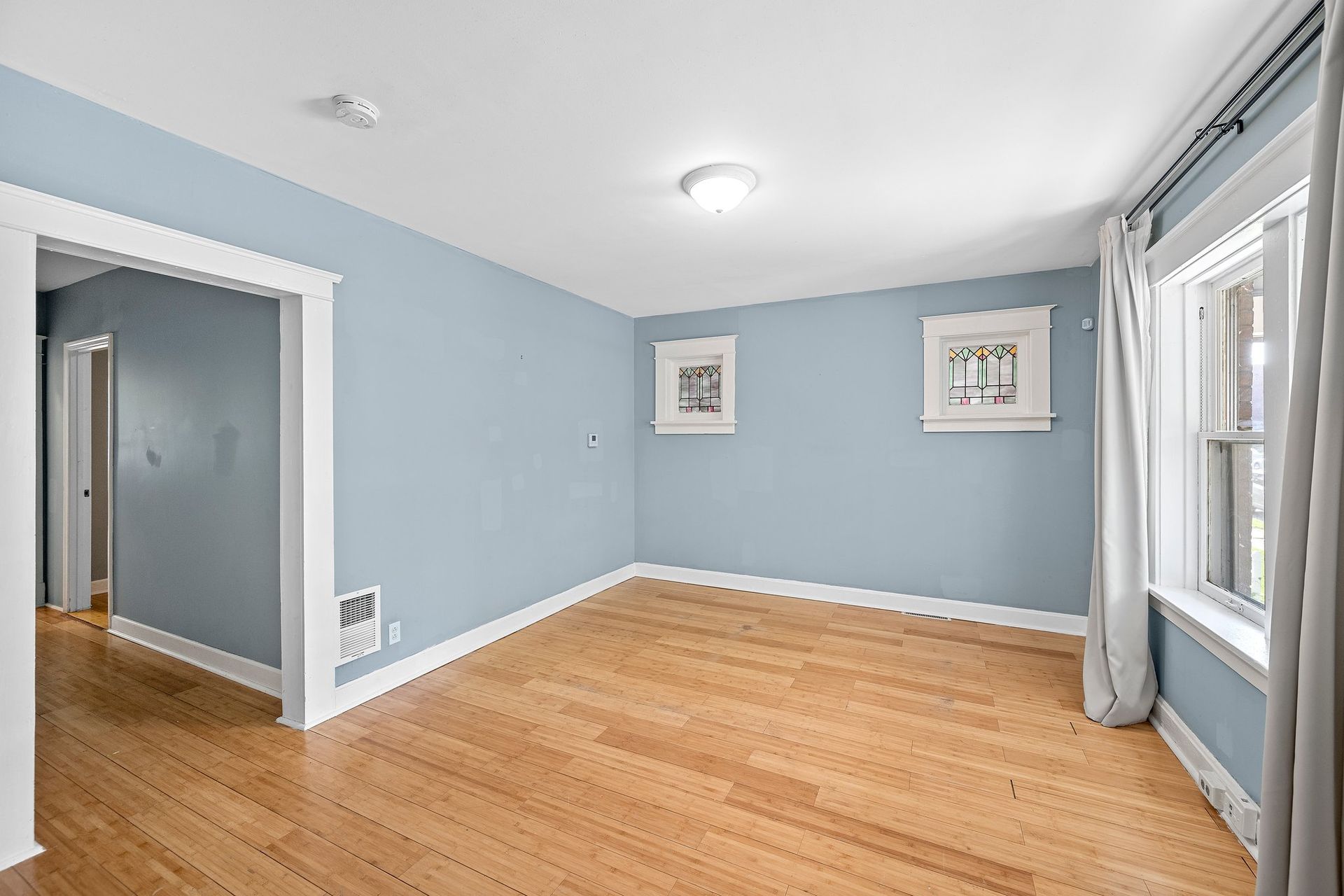 An empty living room with blue walls and hardwood floors.