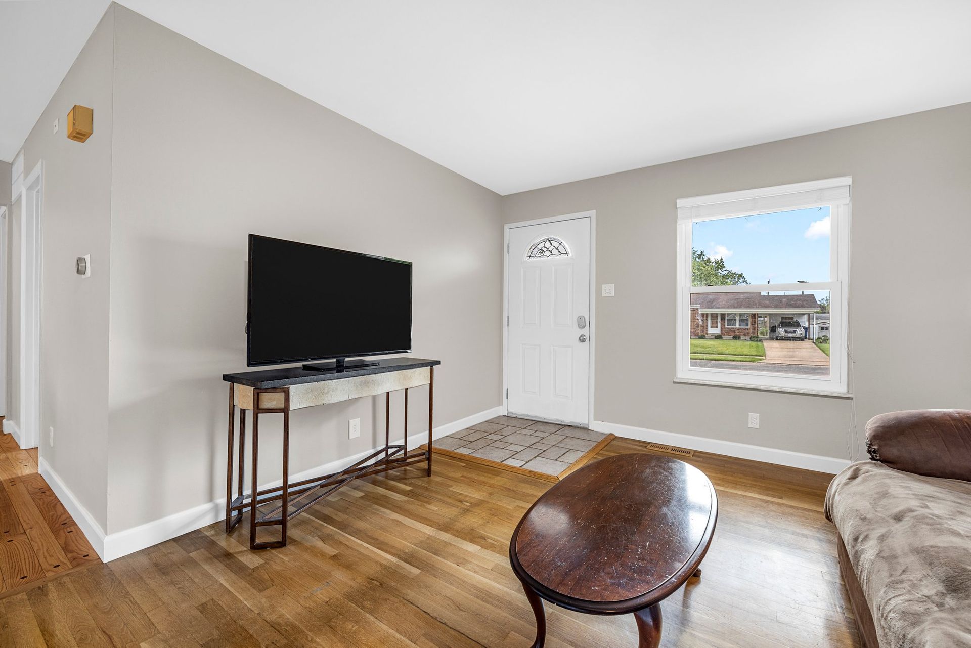 A living room with hardwood floors and a flat screen tv on the wall.