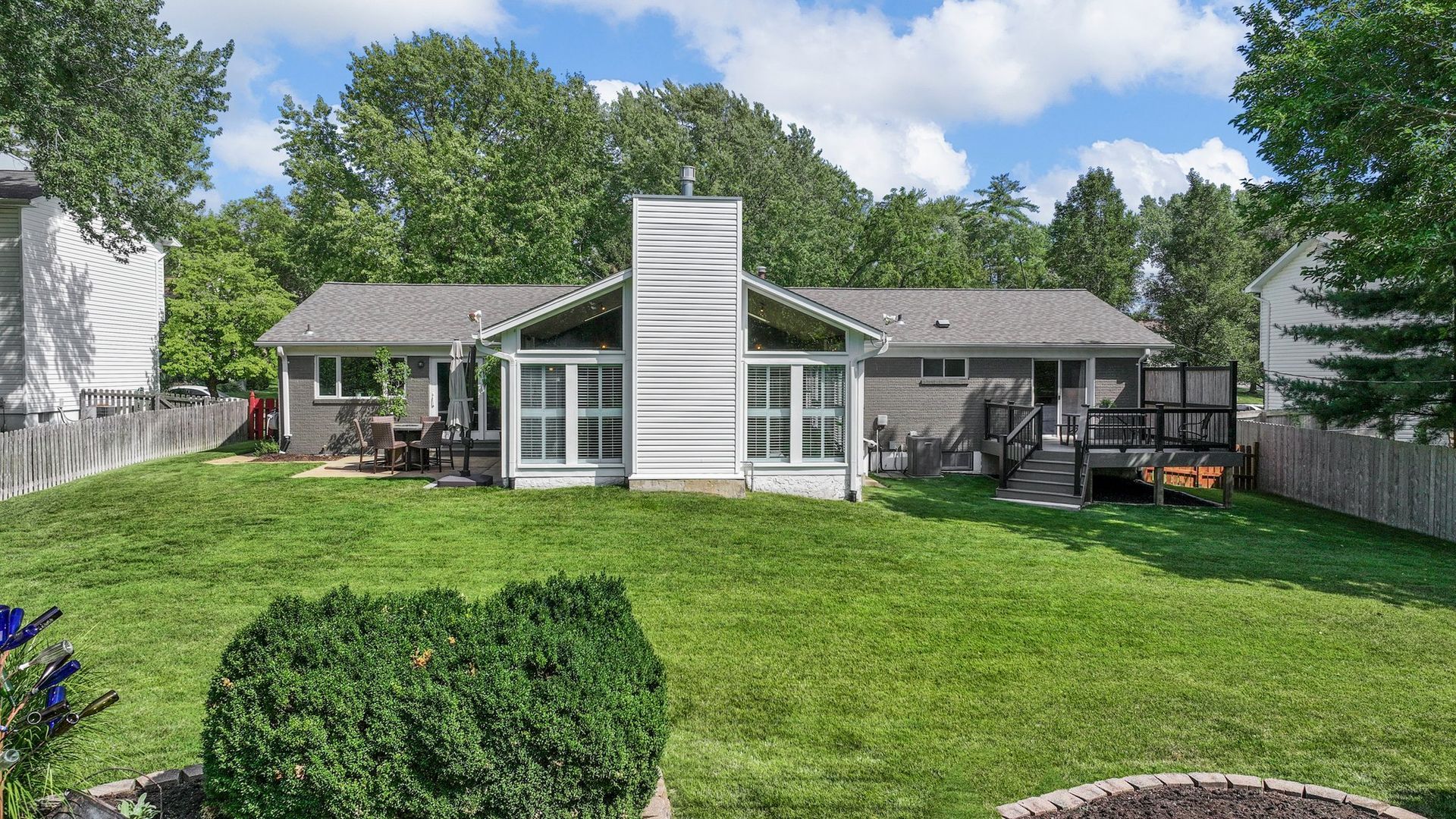 The backyard of a house with a large lawn and a fence.