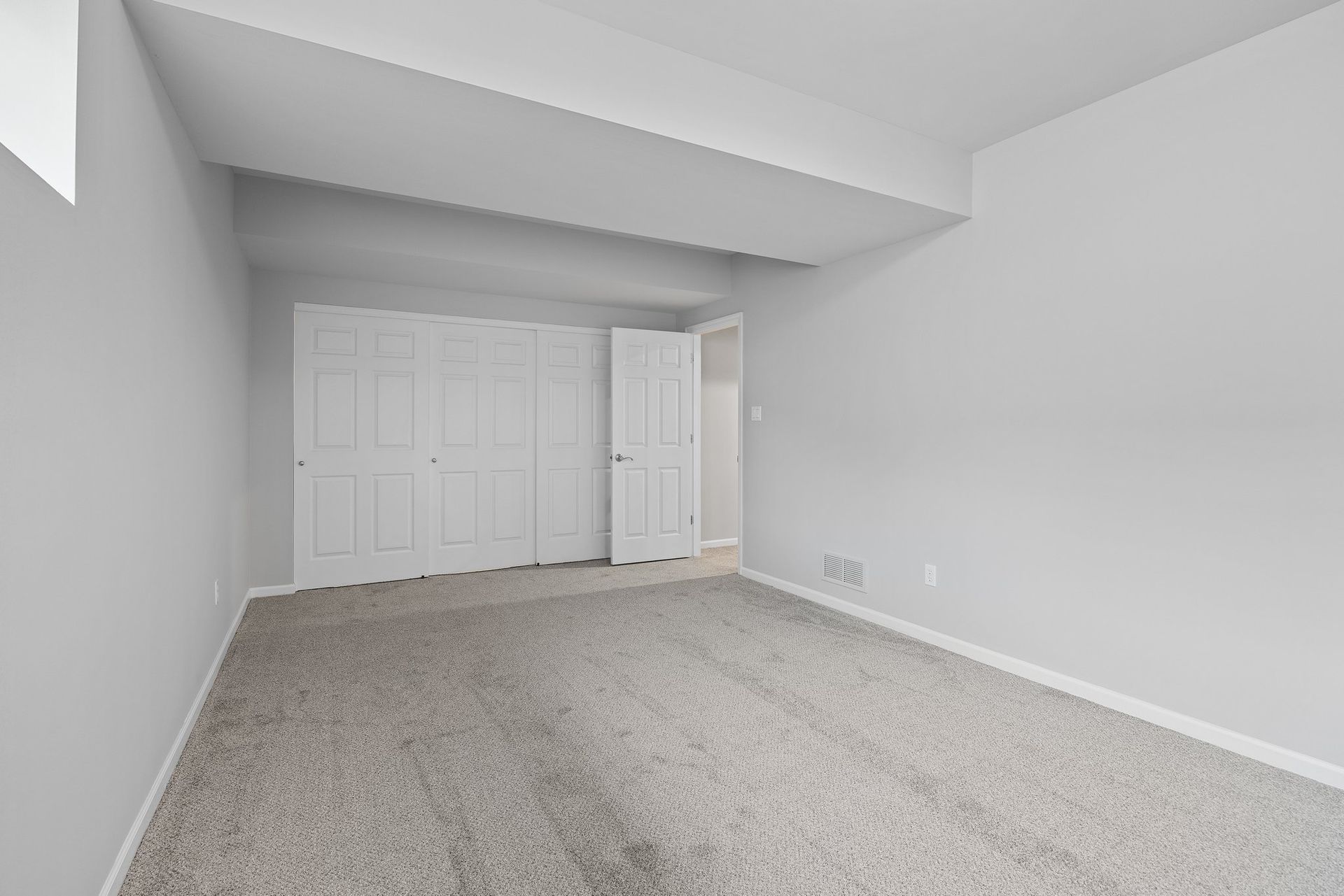 An empty bedroom with a carpeted floor and white walls.