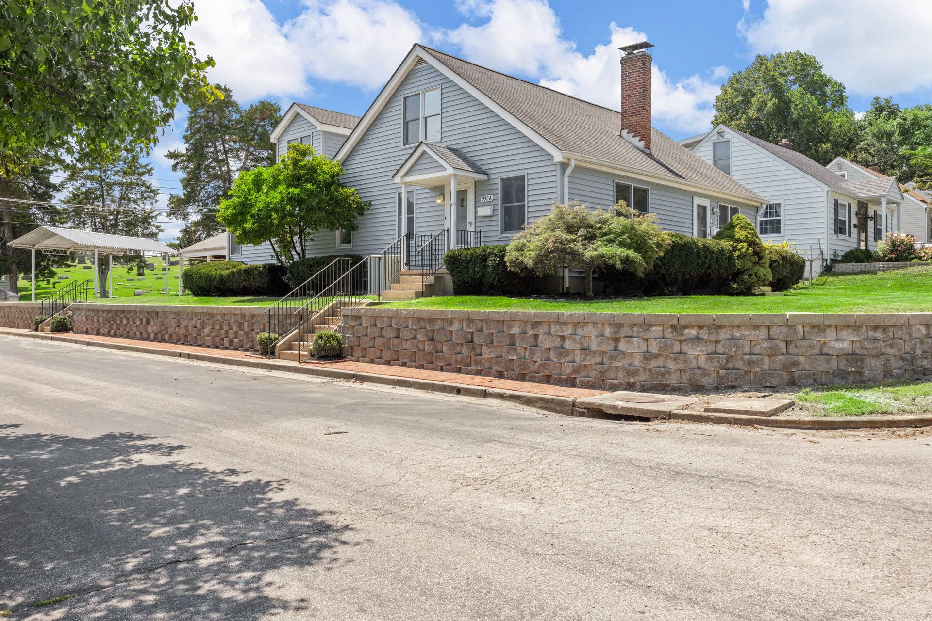 A white house with a stone wall in front of it