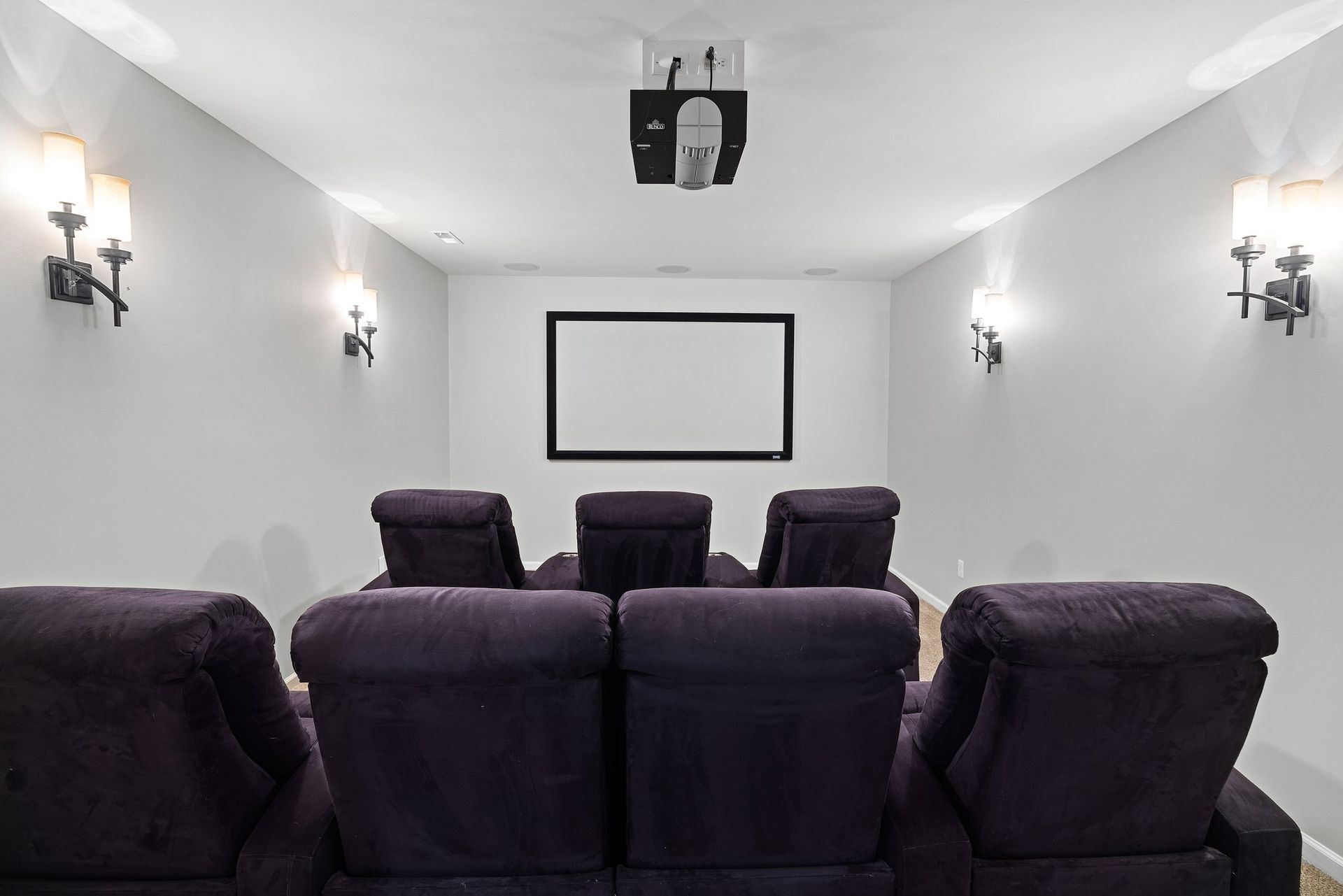 A home theater with purple chairs and a projector screen.