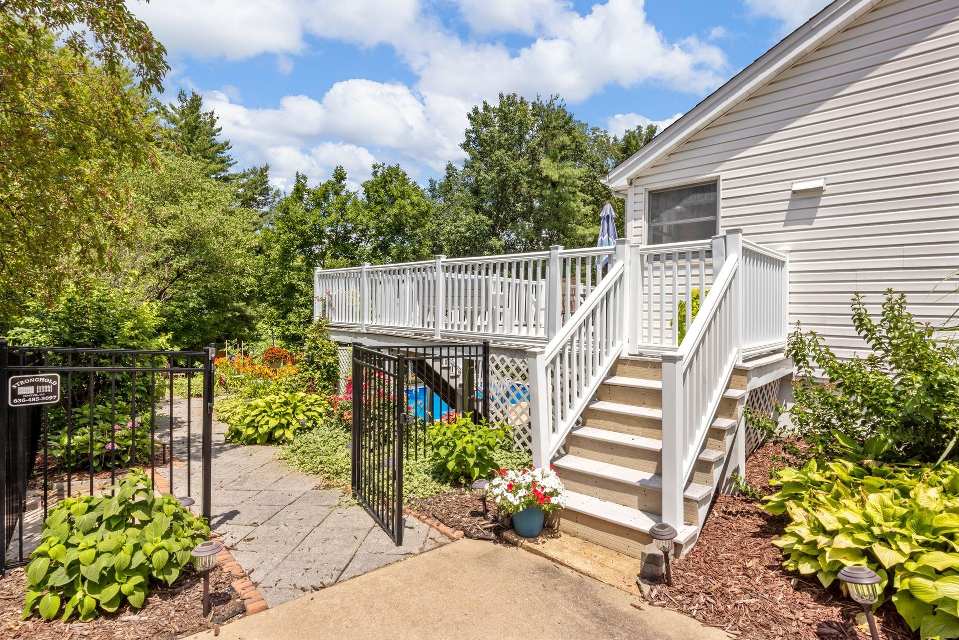 A white house with a large deck and stairs leading up to it.