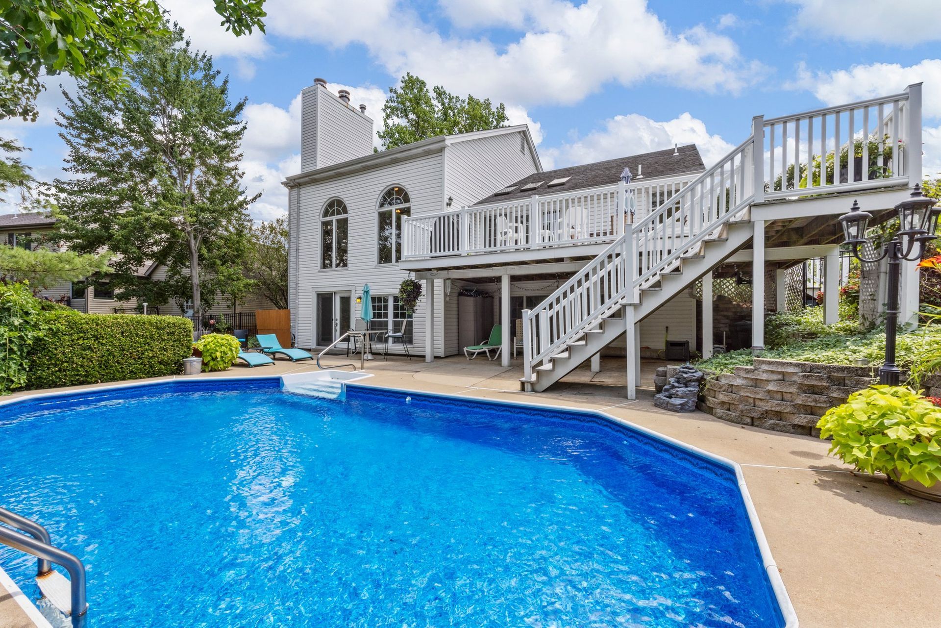 There is a large swimming pool in the backyard of a house.