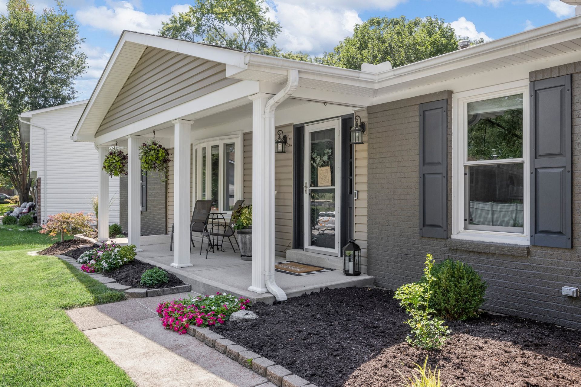 The front of a house with a porch and shutters.