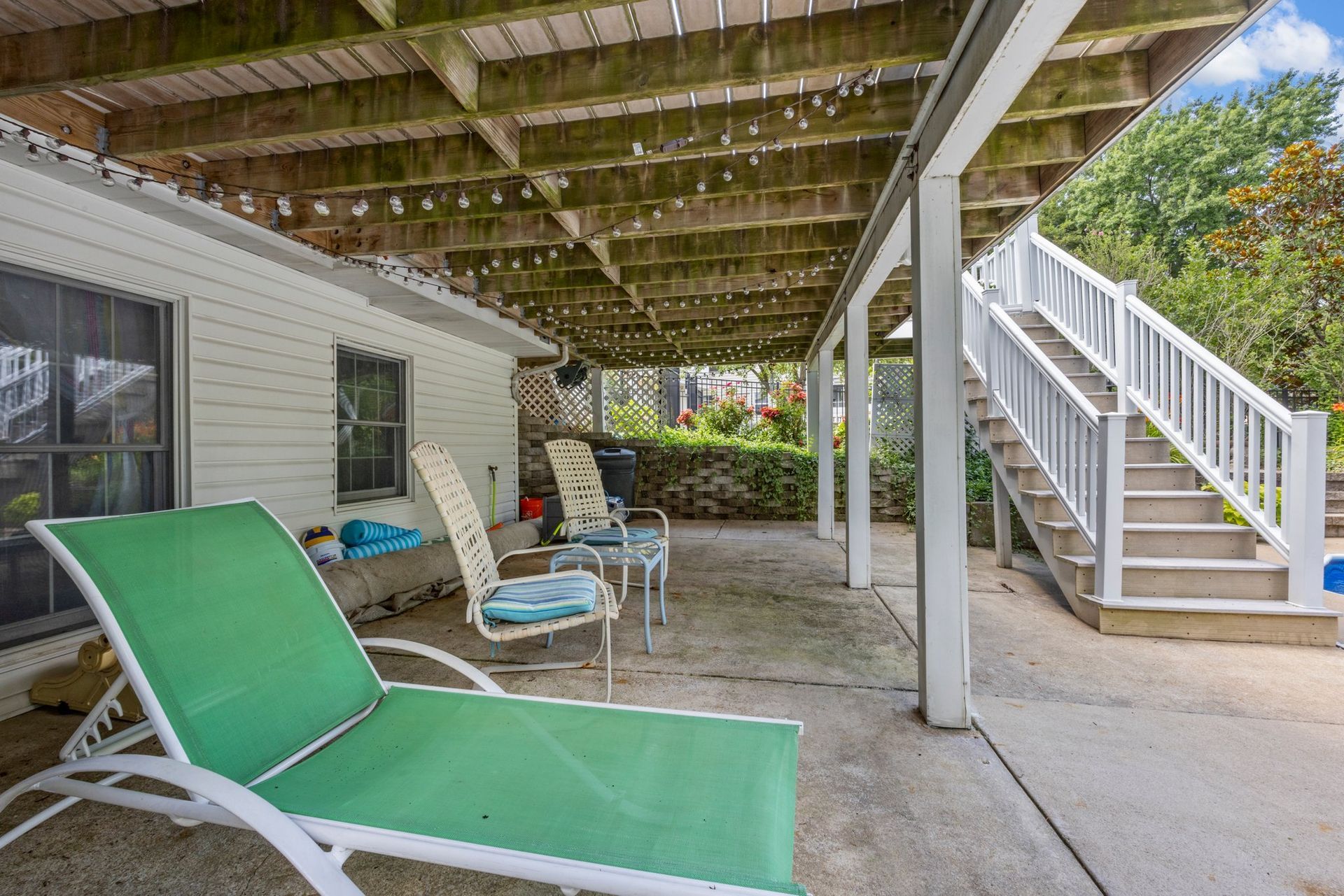 A patio with chairs and stairs next to a house.