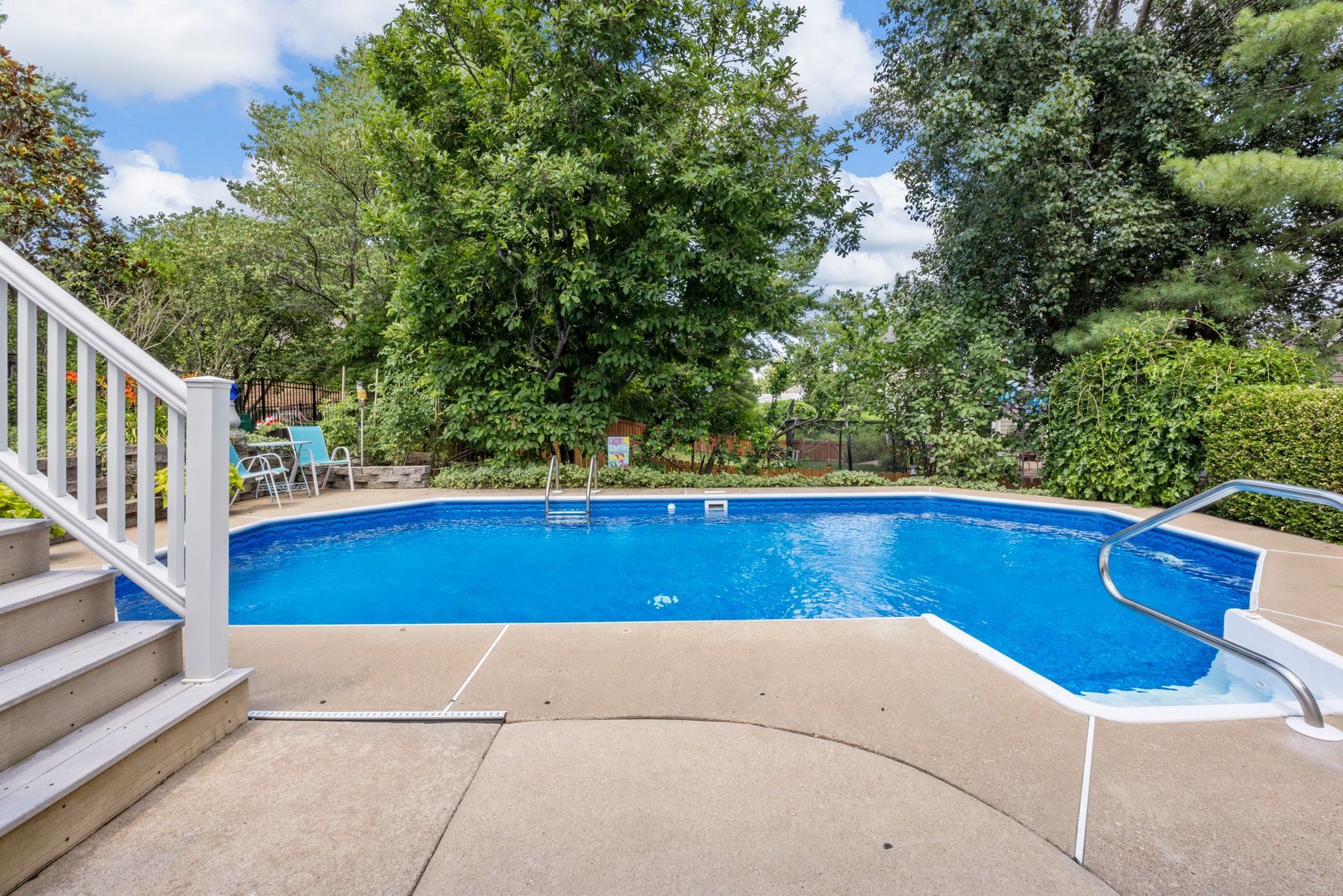 There is a large swimming pool in the backyard with stairs leading to it.