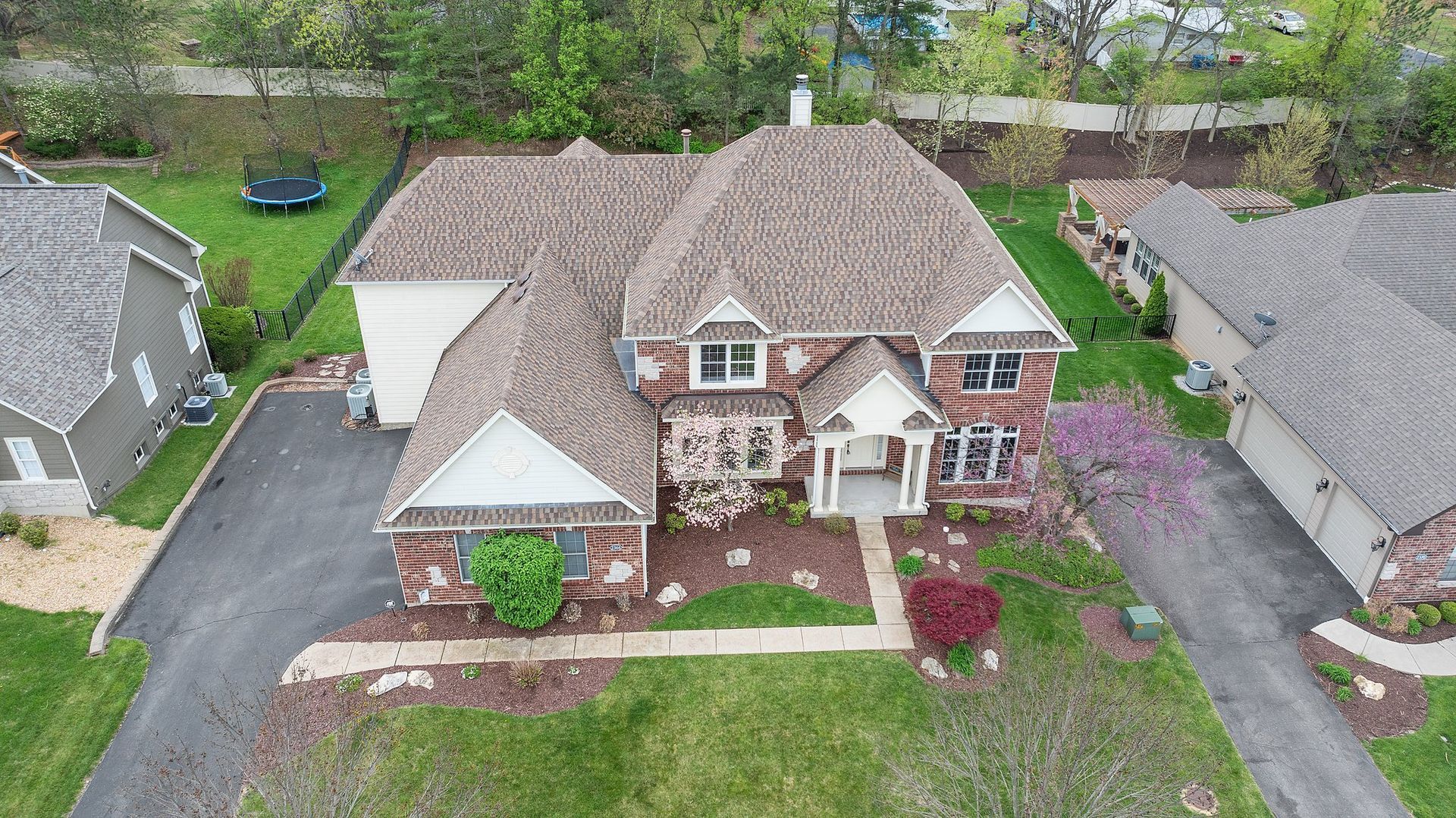 An aerial view of a house with a trampoline in the backyard.