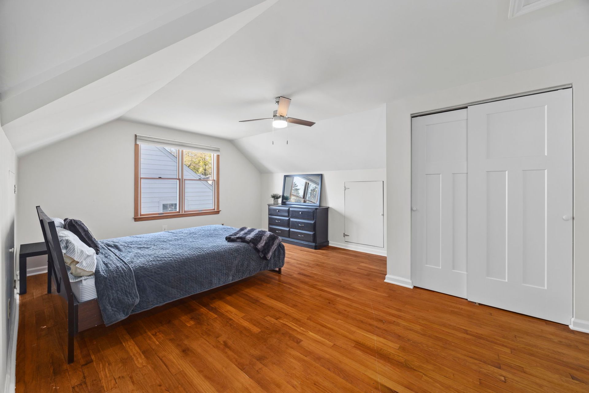 A bedroom with a bed , dresser , and ceiling fan.