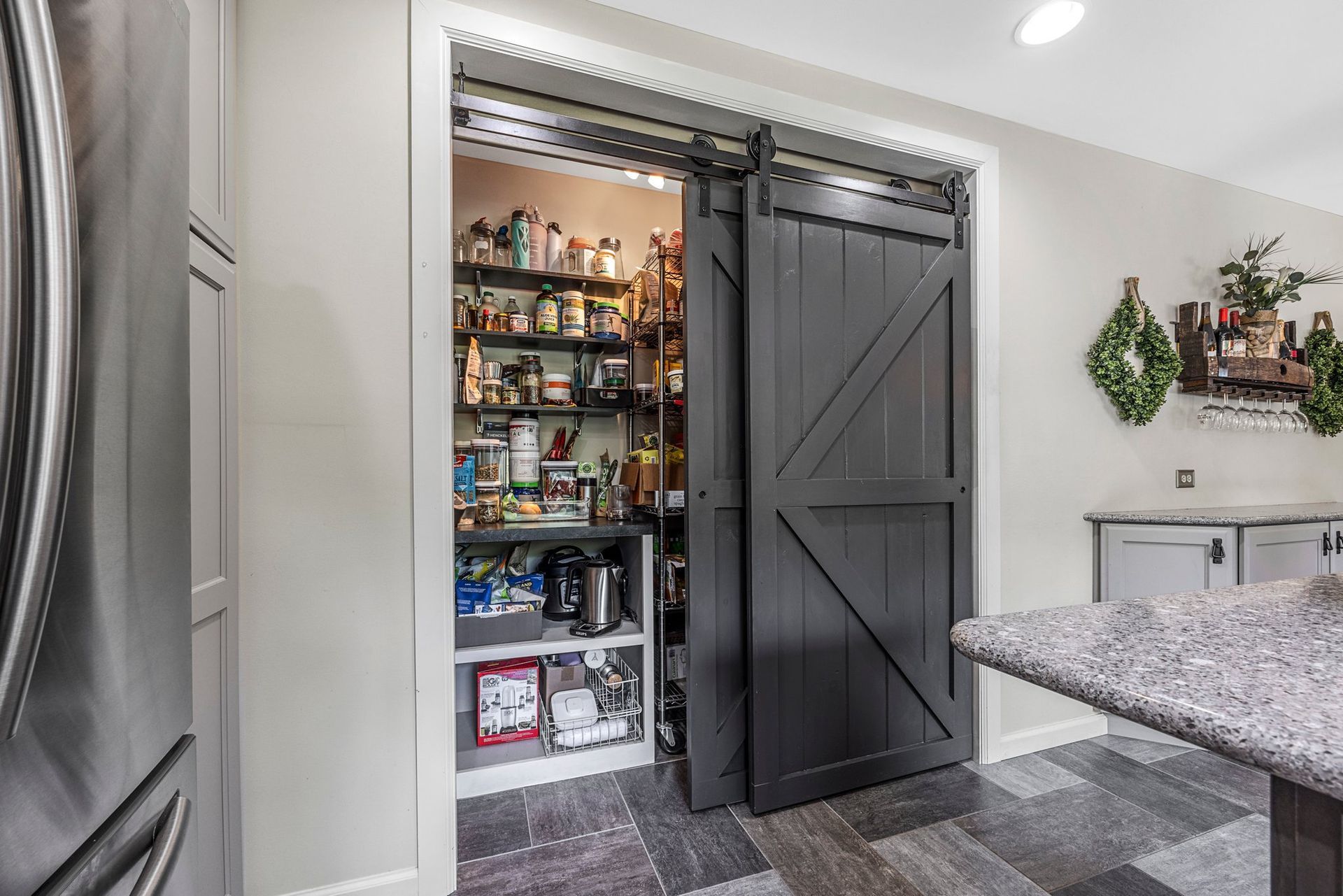 A kitchen with a sliding barn door leading to a pantry.