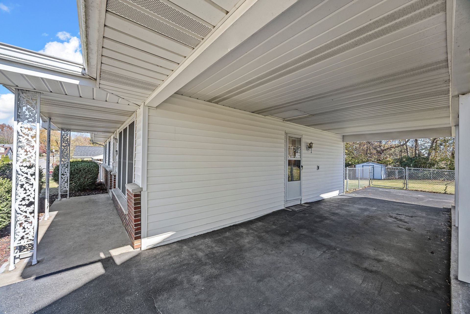 A white house with a carport and a walkway leading to it.