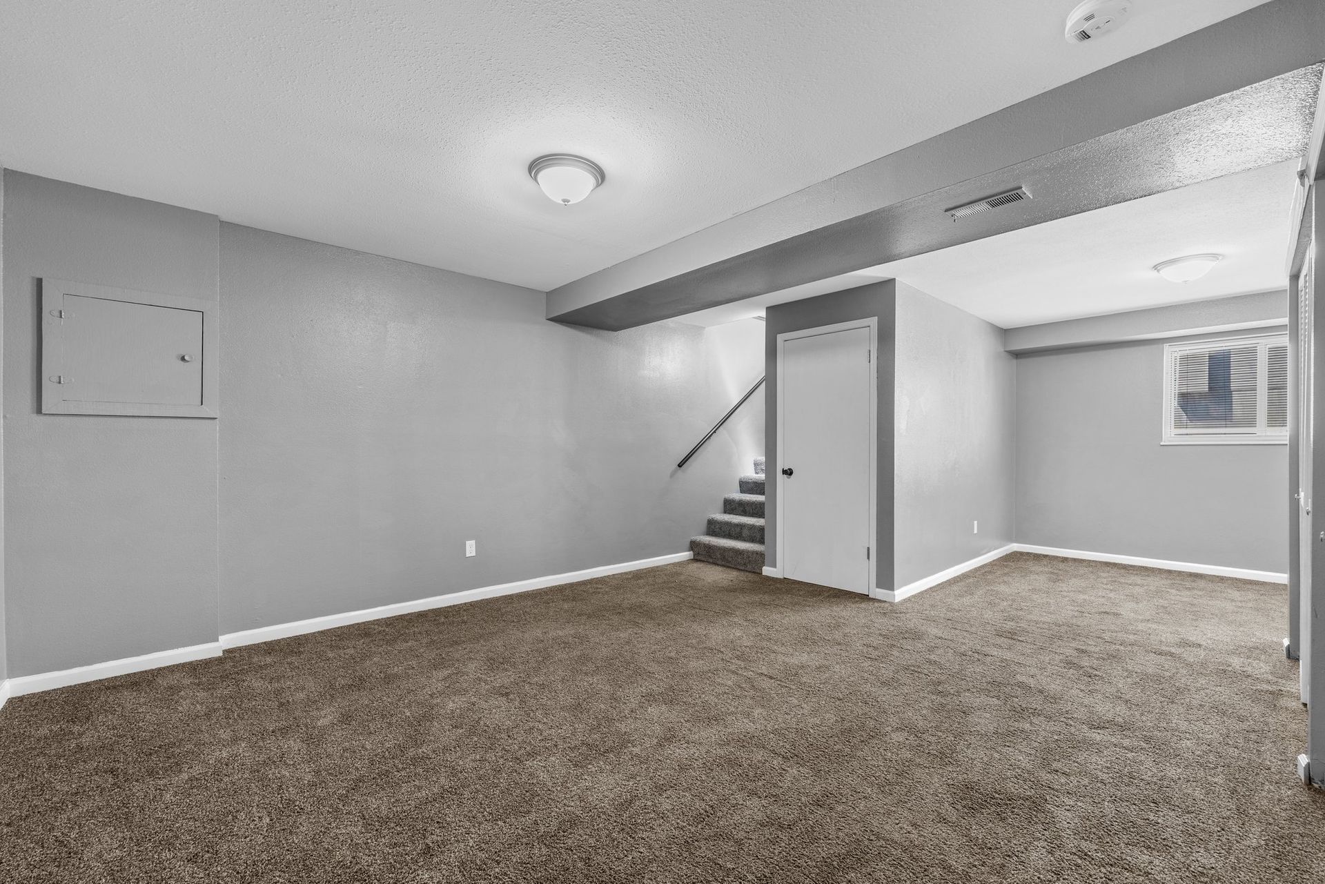 An empty basement with a staircase leading up to the second floor.