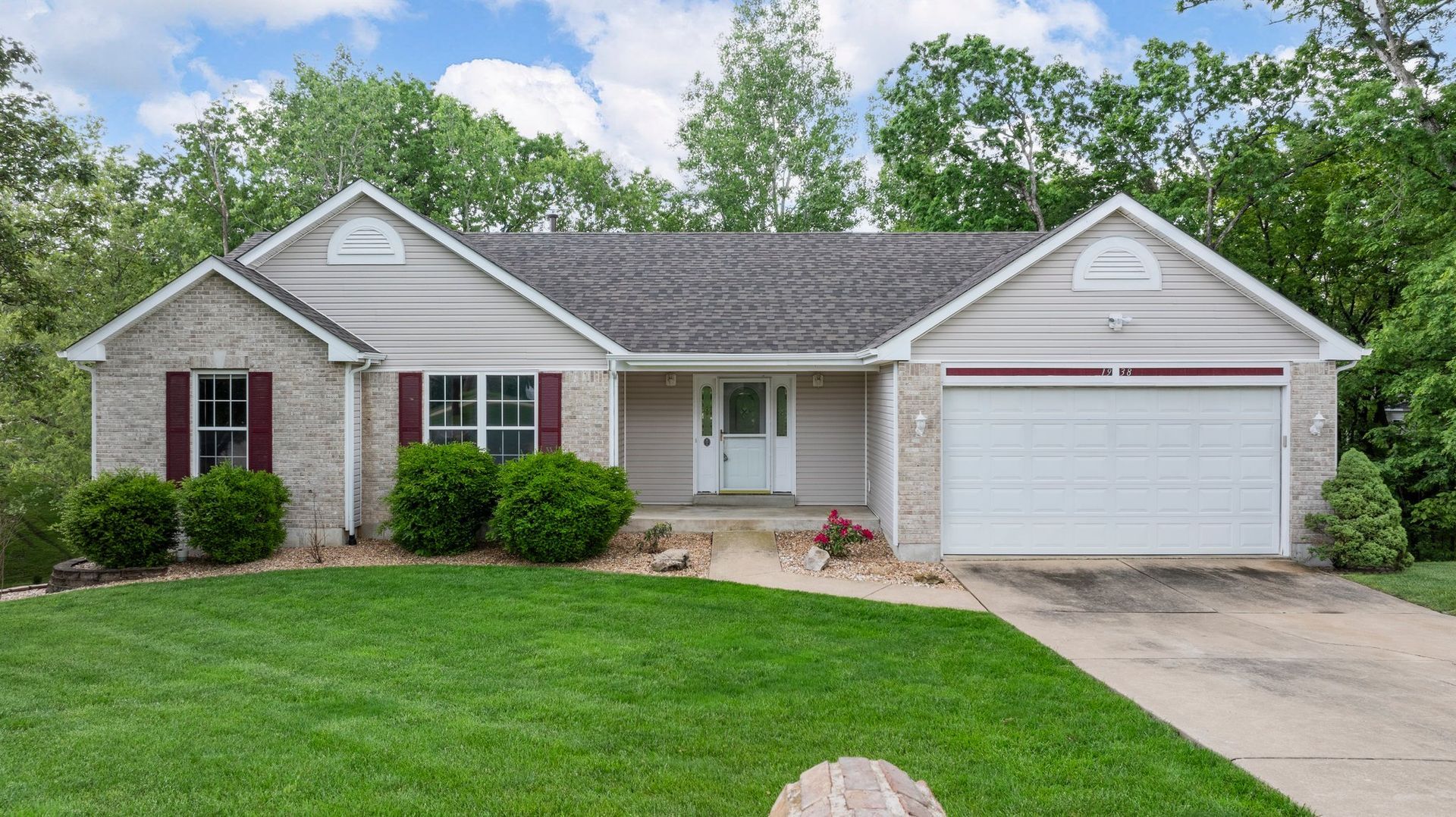 A house with a white garage door and a large lawn in front of it.