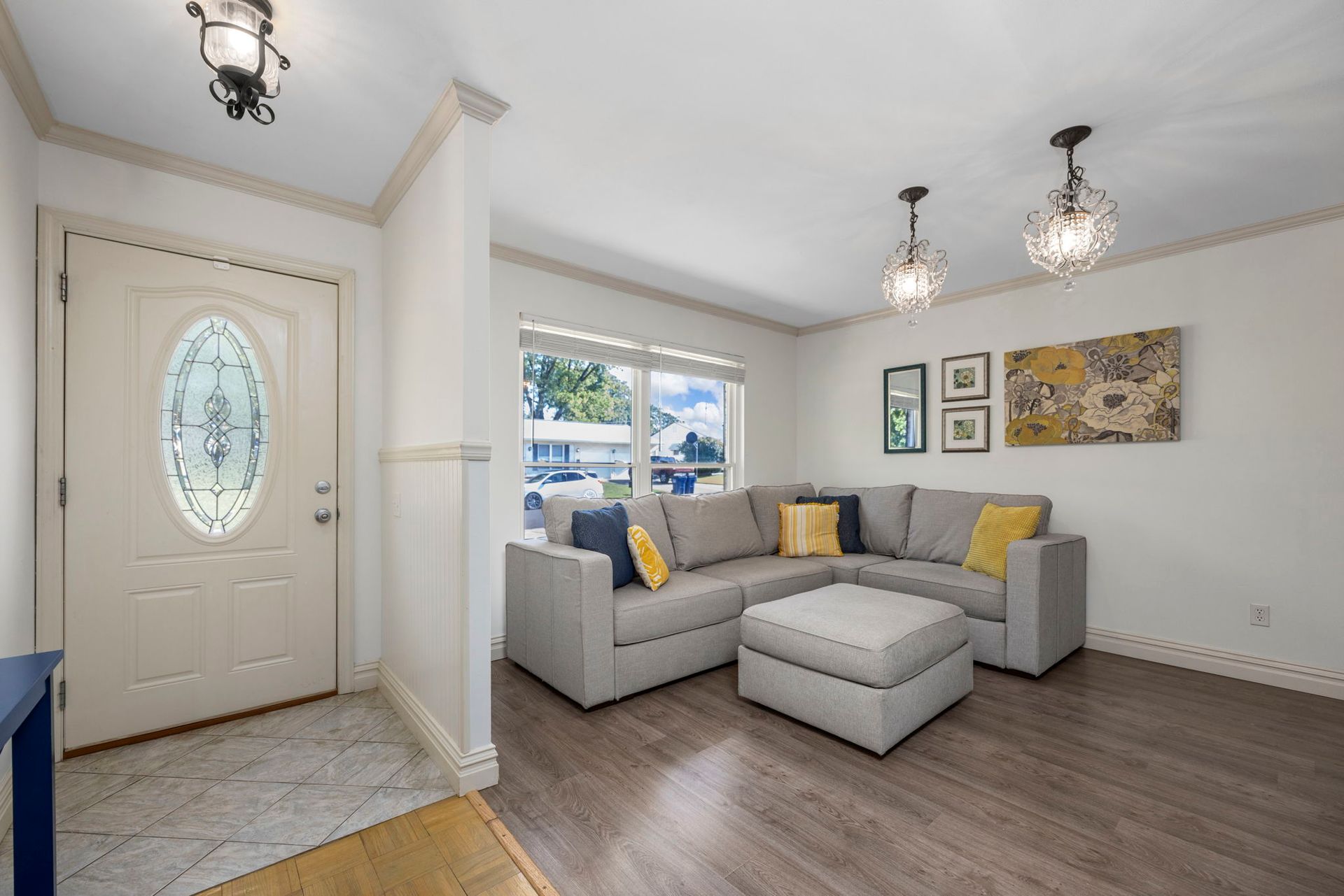 A living room with a gray sectional, decorative lighting, and a front door.