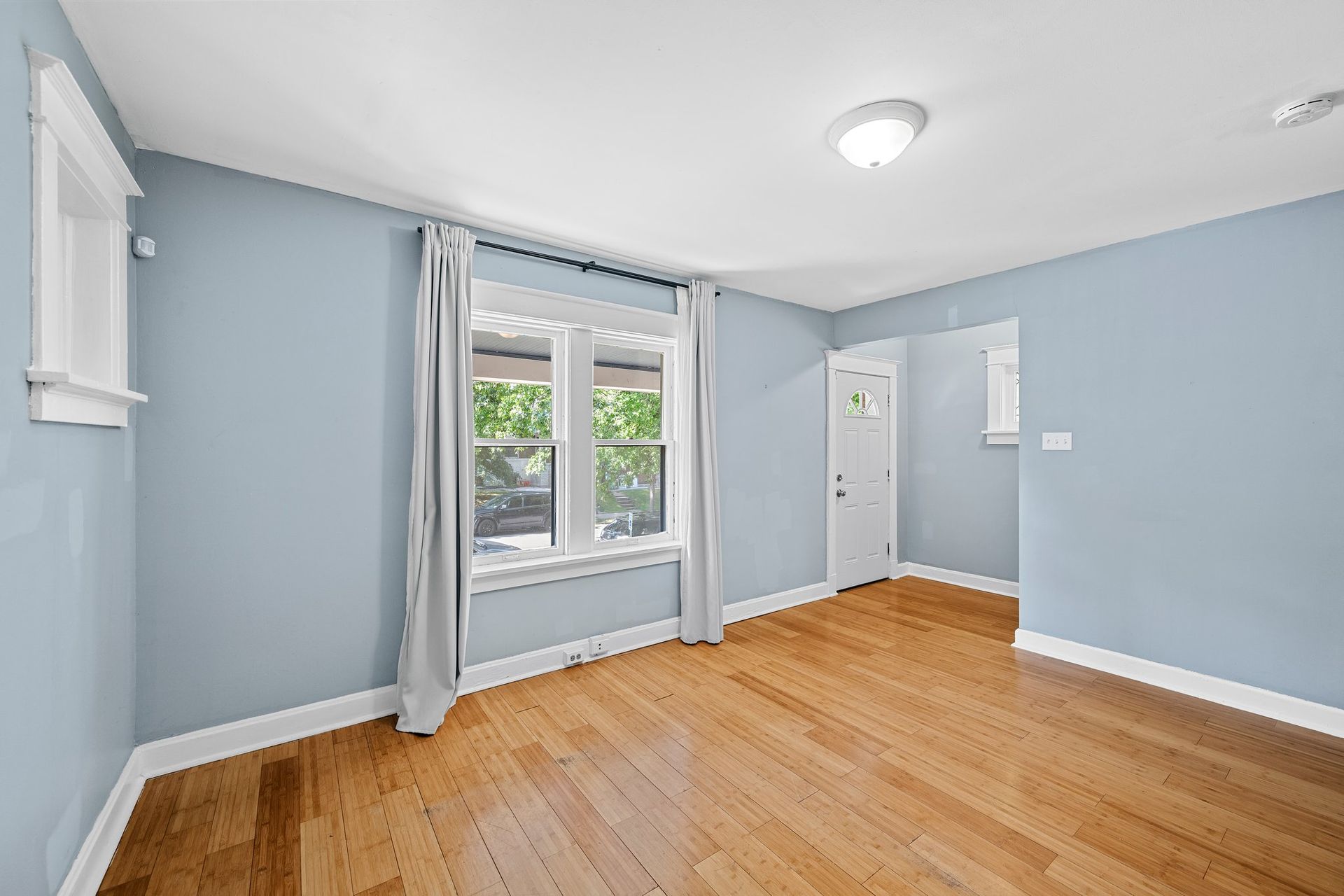 An empty living room with hardwood floors and blue walls.