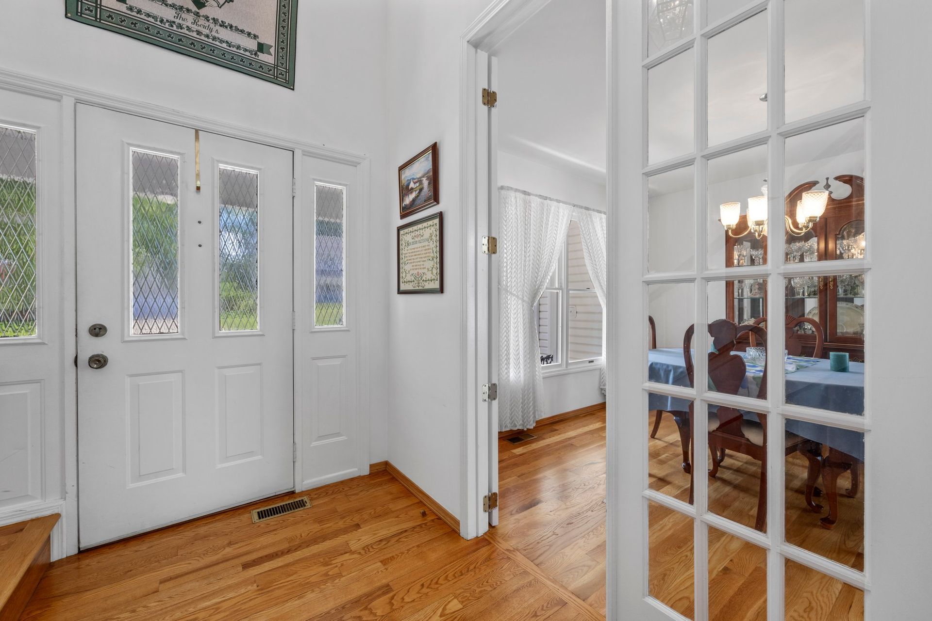 A hallway with hardwood floors and white doors leading to a dining room.