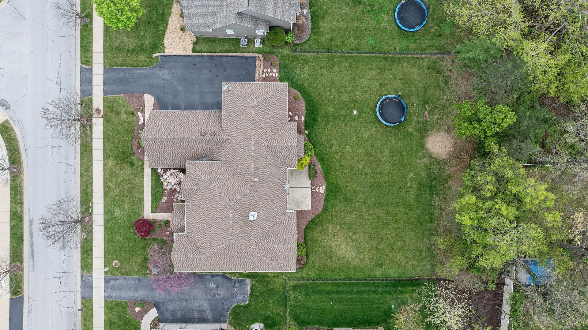 An aerial view of a house with a trampoline in the backyard.
