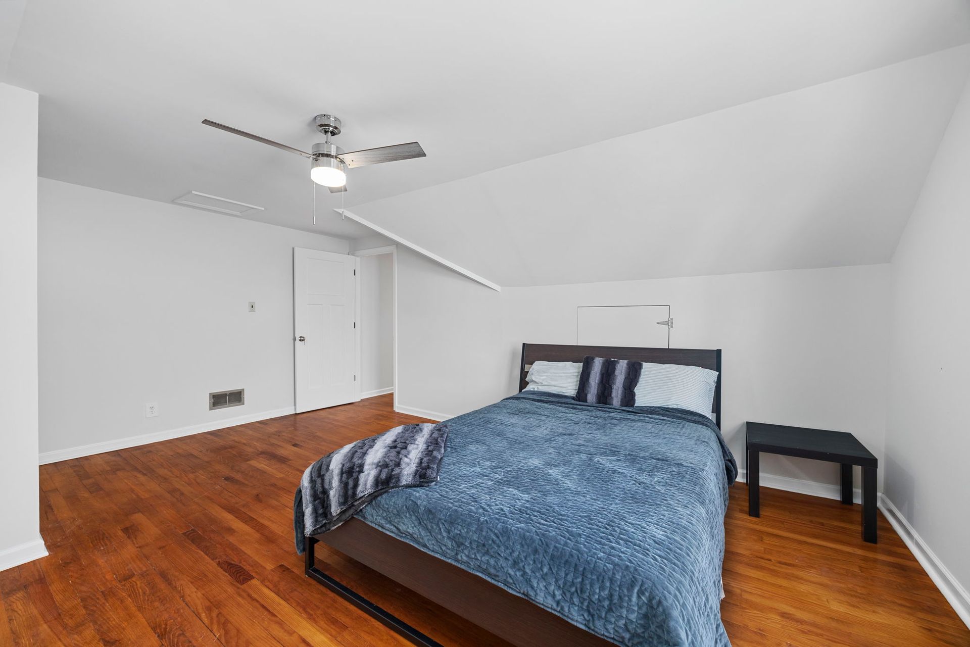 A bedroom with a bed and a ceiling fan.