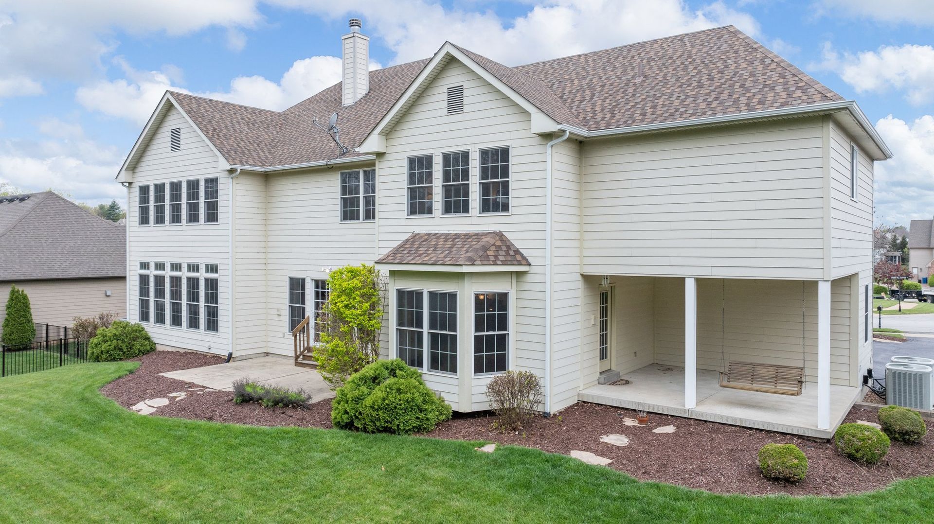 A large white house with a brown roof is sitting on top of a lush green lawn.