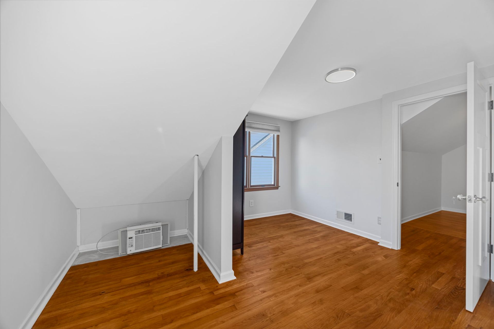An empty room with hardwood floors and white walls.