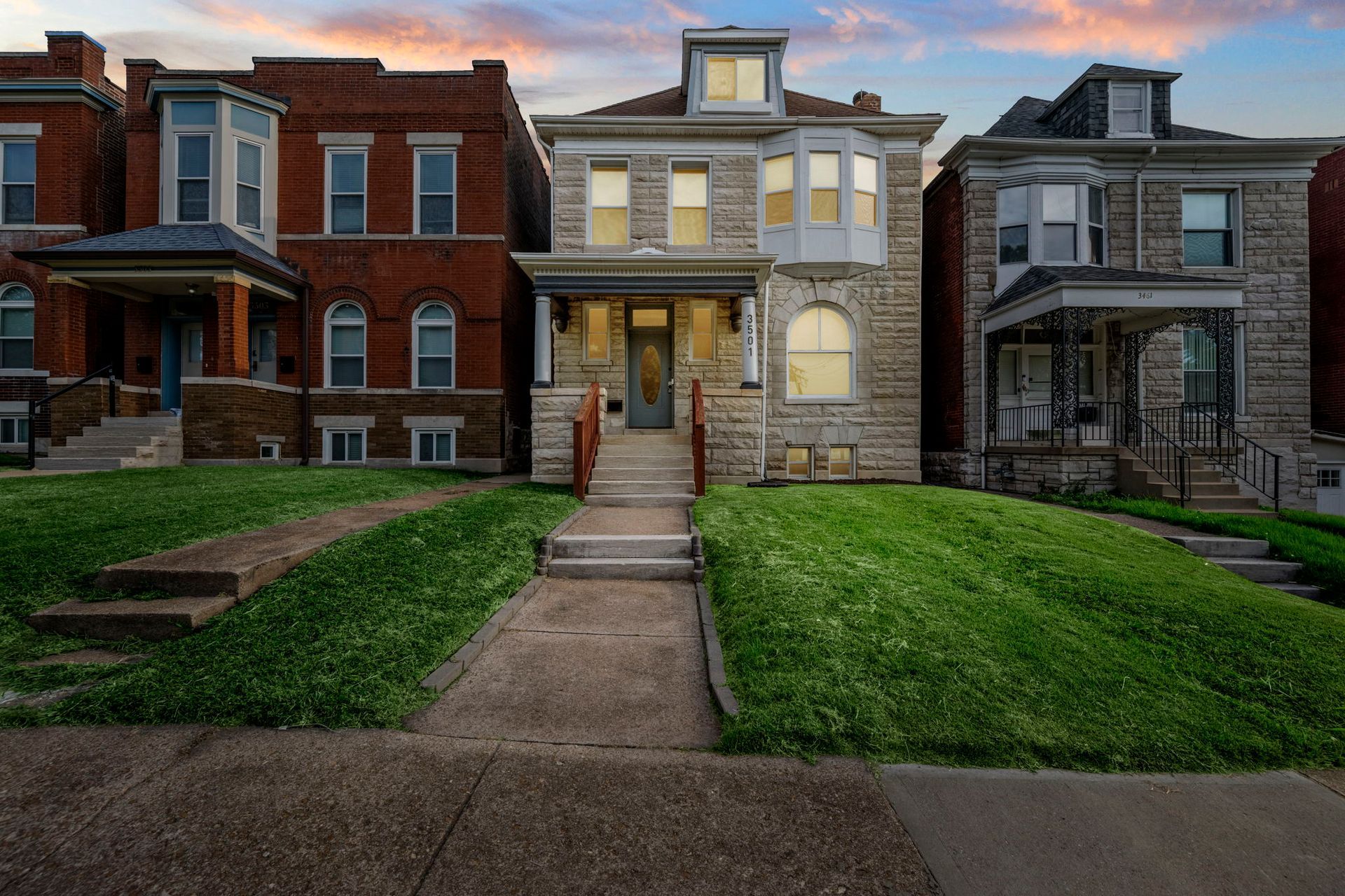 A large white house with two garages and a lush green yard.