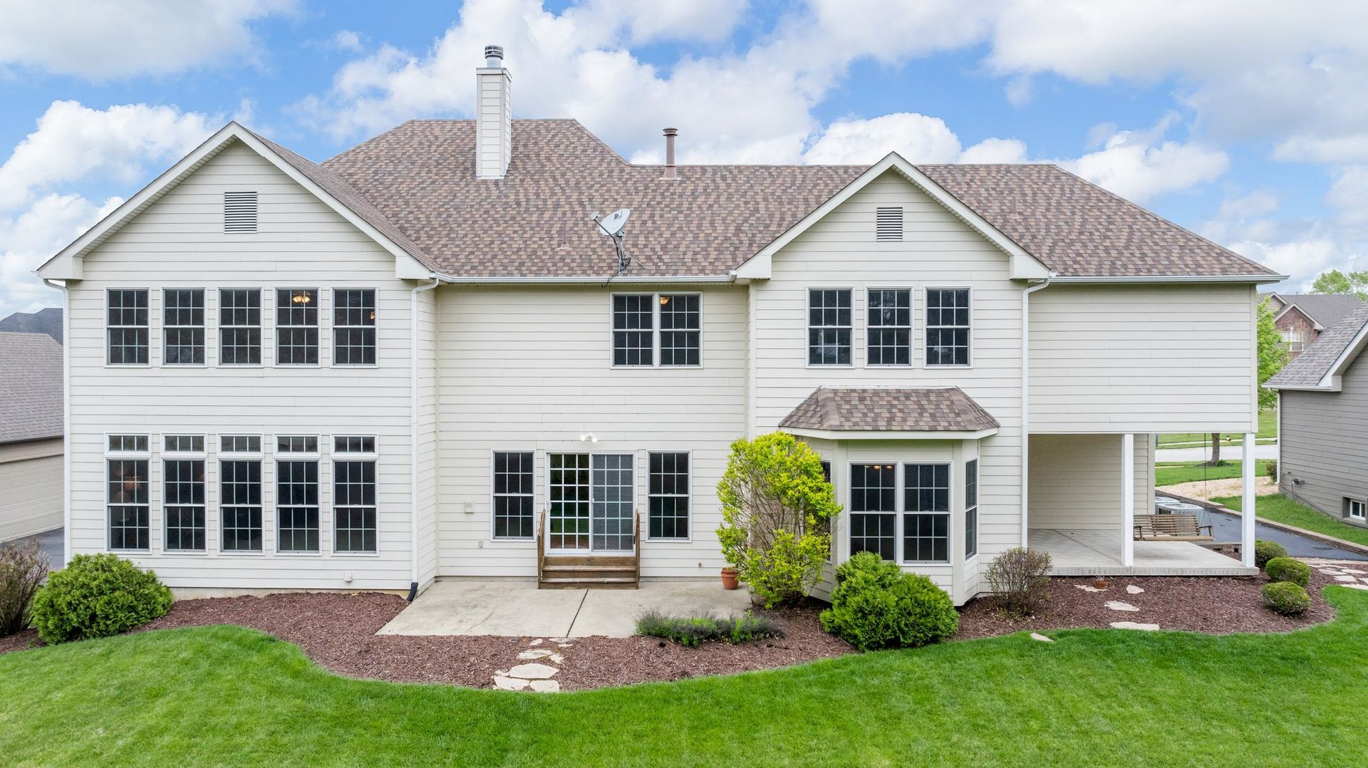 A large white house with a lot of windows is sitting on top of a lush green lawn.