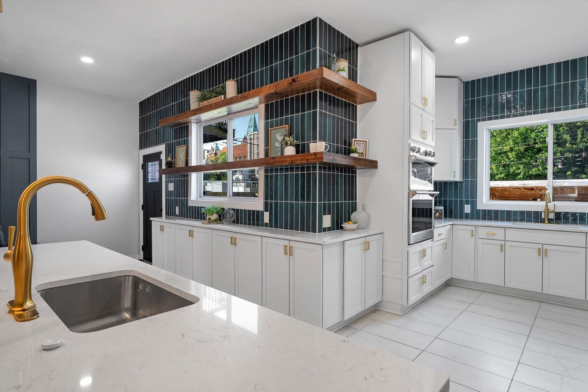 Modern kitchen with white cabinets, blue tile accent wall, and gold faucet.