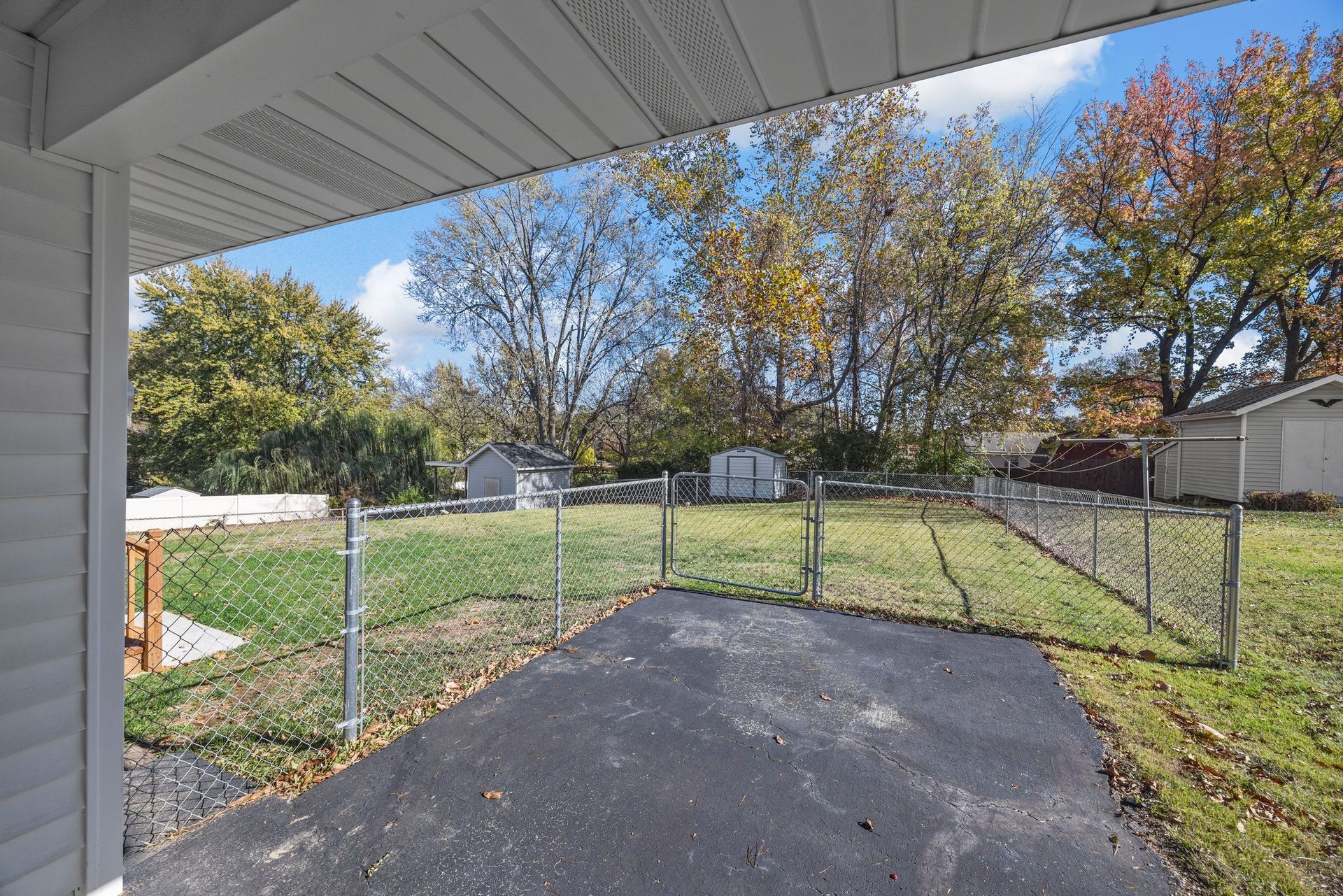 A driveway leading to a house with a fence and trees in the background.