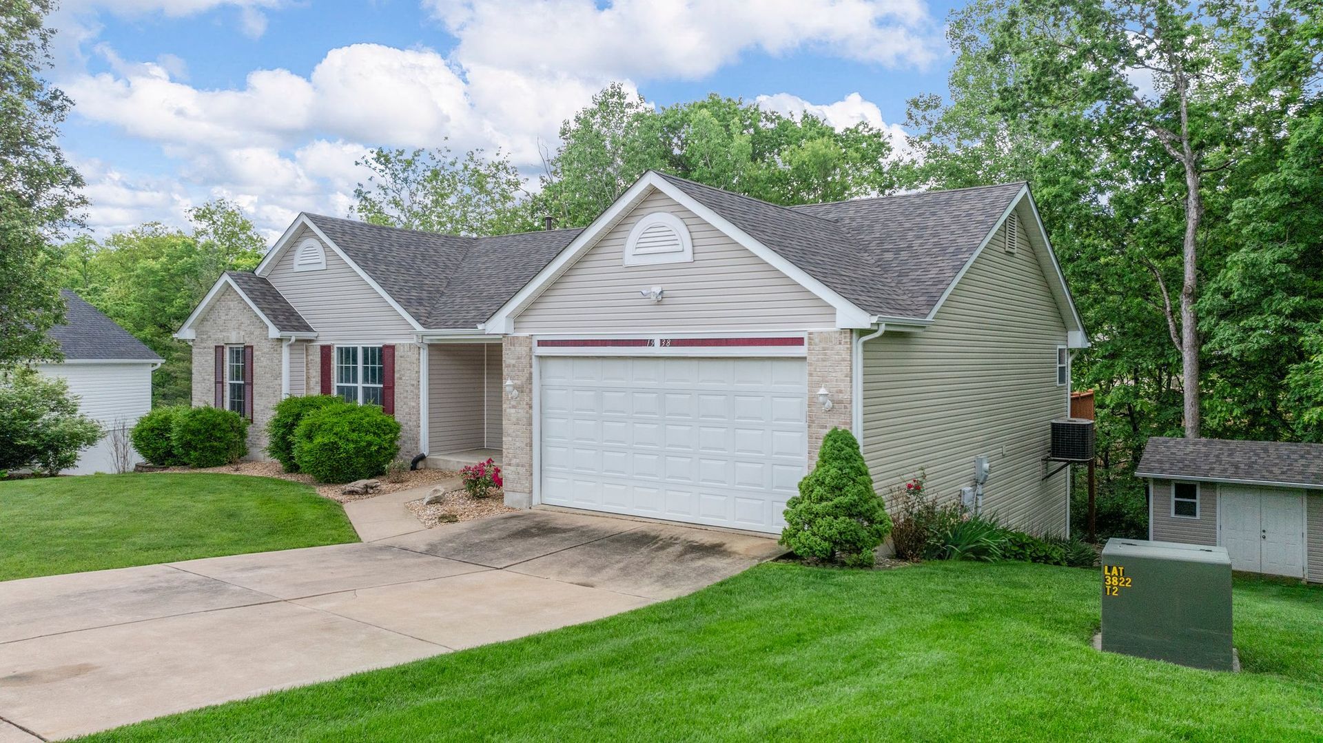 A house with a white garage door is sitting on top of a lush green lawn.