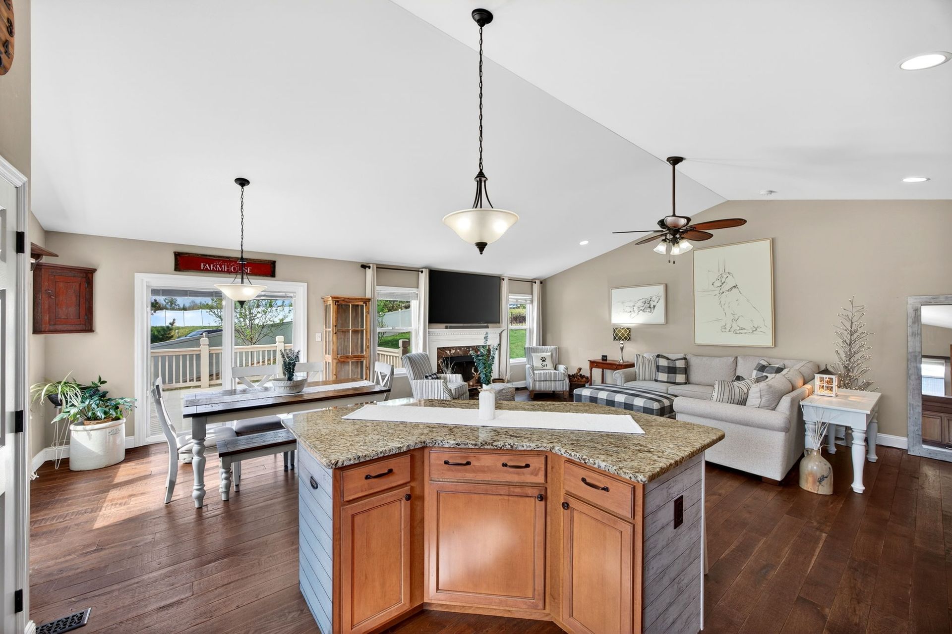 An open-concept living area with a kitchen island, dining table, and cozy seating area on hardwood floors.