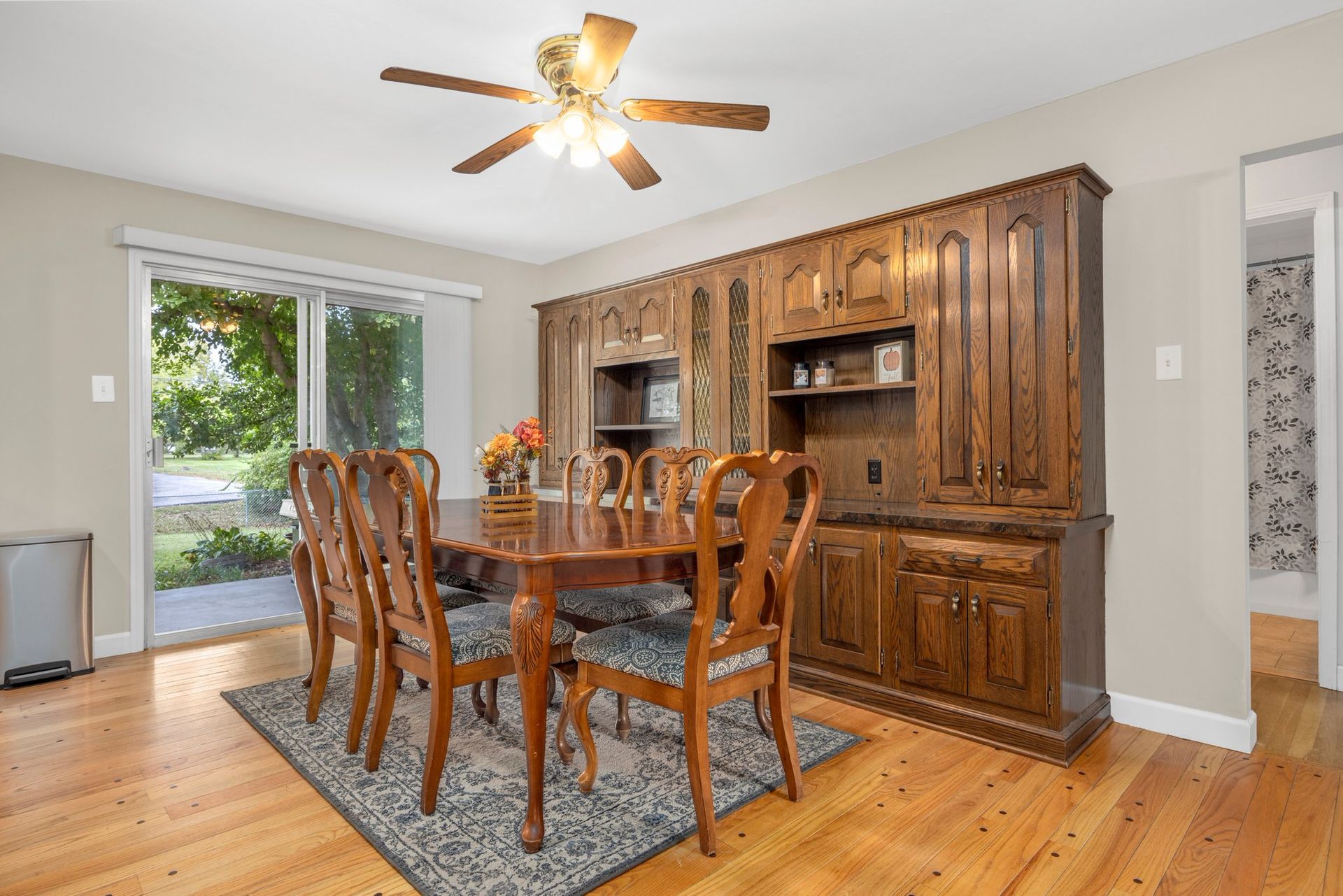 A dining room with a table and chairs and a ceiling fan.