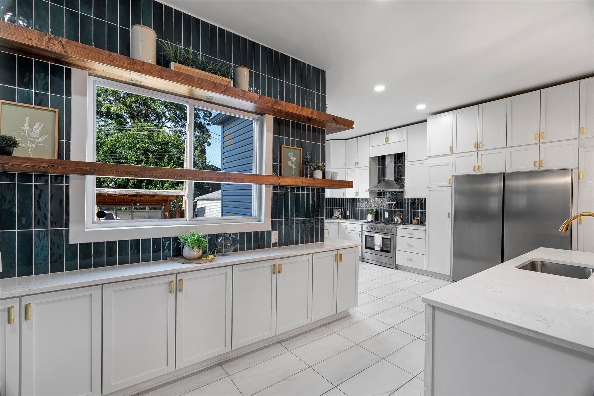 Modern kitchen with white cabinets, marble countertops, stainless steel appliances, and a dark tiled accent wall.