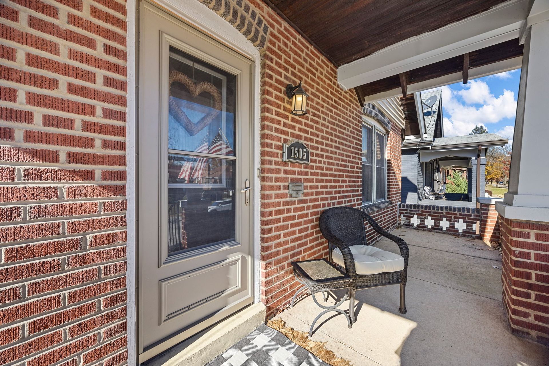There is a chair on the porch of a brick house.