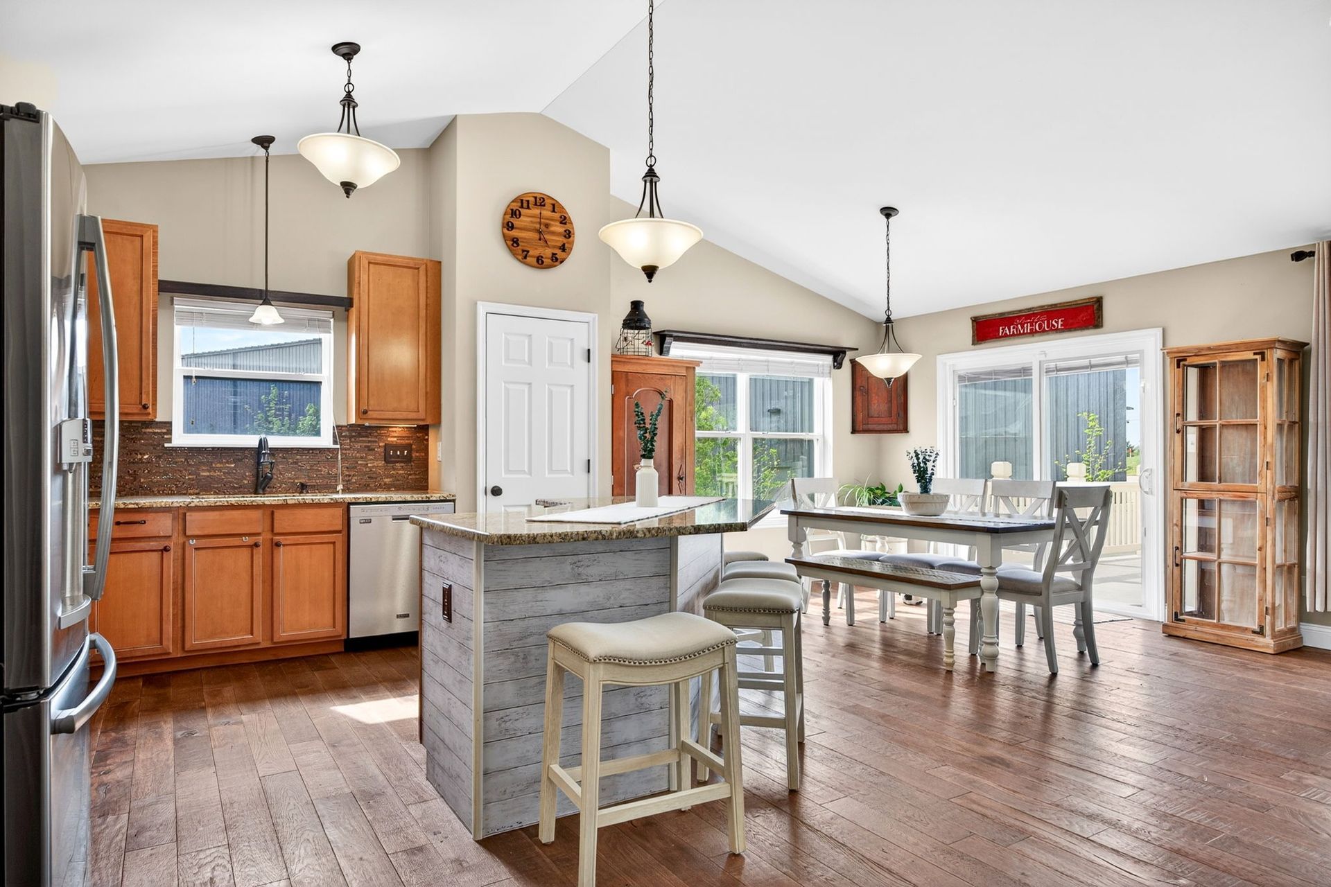 Bright, open-concept kitchen with light-wood cabinets, a distressed kitchen island, and a wooden dining table.