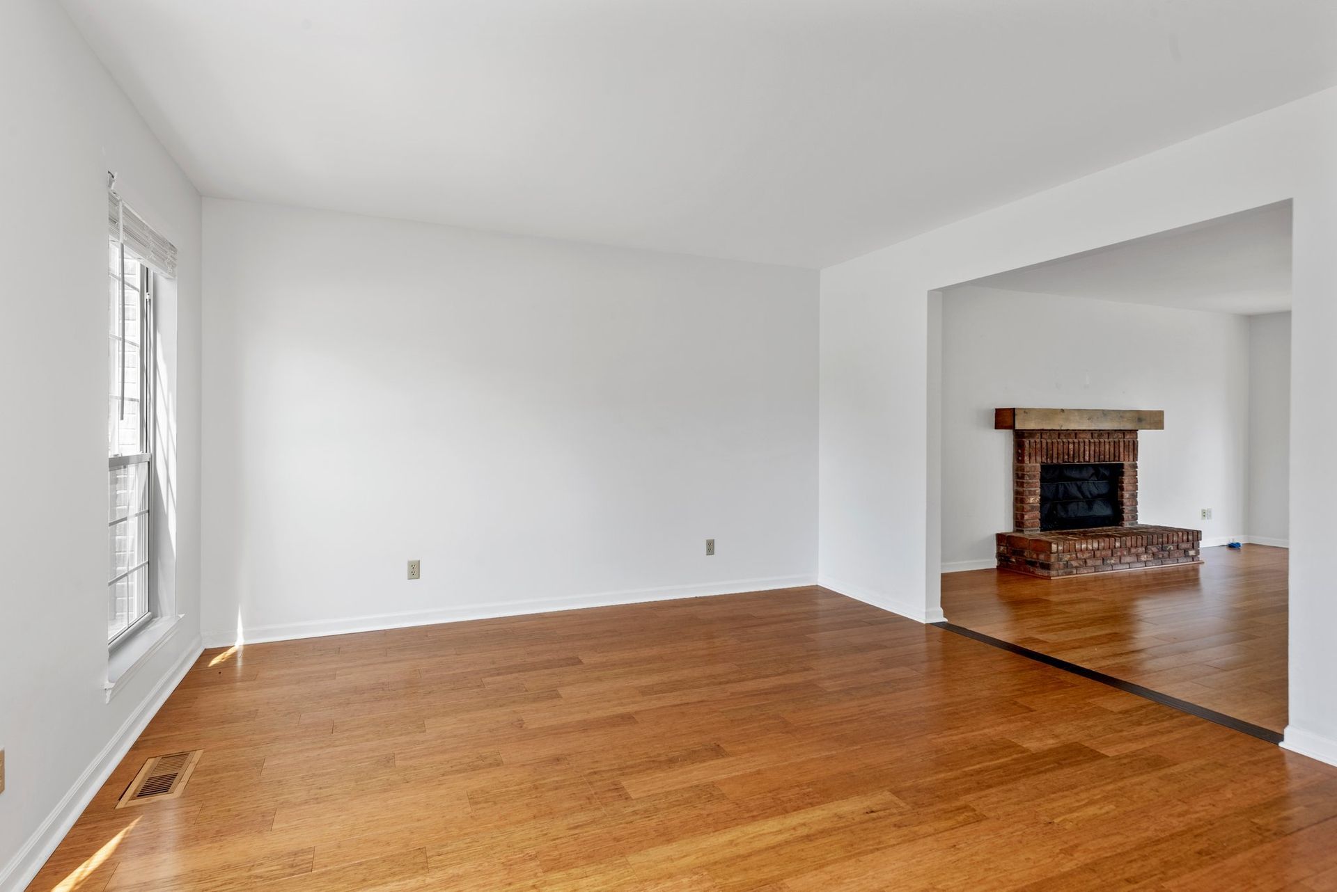 An empty living room with hardwood floors and a fireplace.