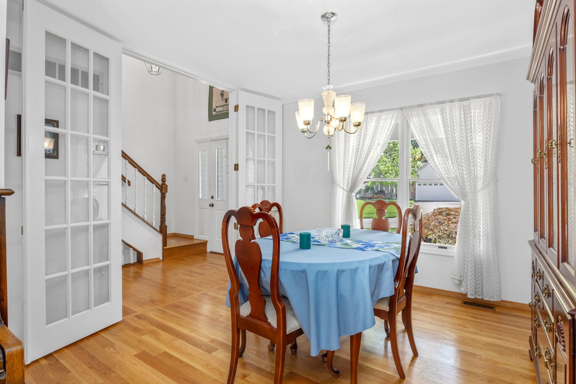 A dining room with a round table and chairs and a blue table cloth.