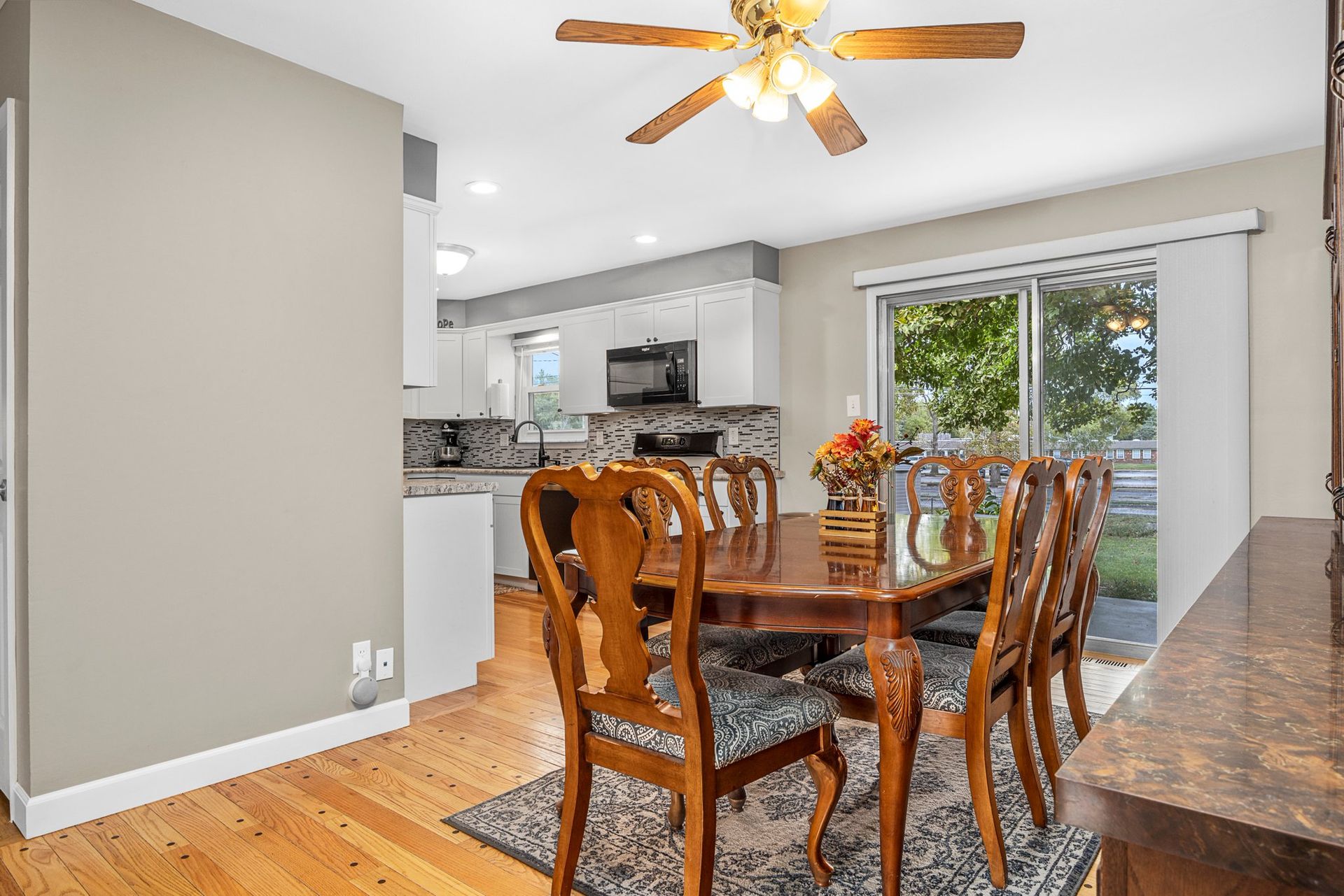 A dining room with a table and chairs and a ceiling fan.