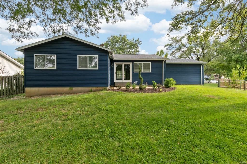 A blue house with a large lawn in front of it.