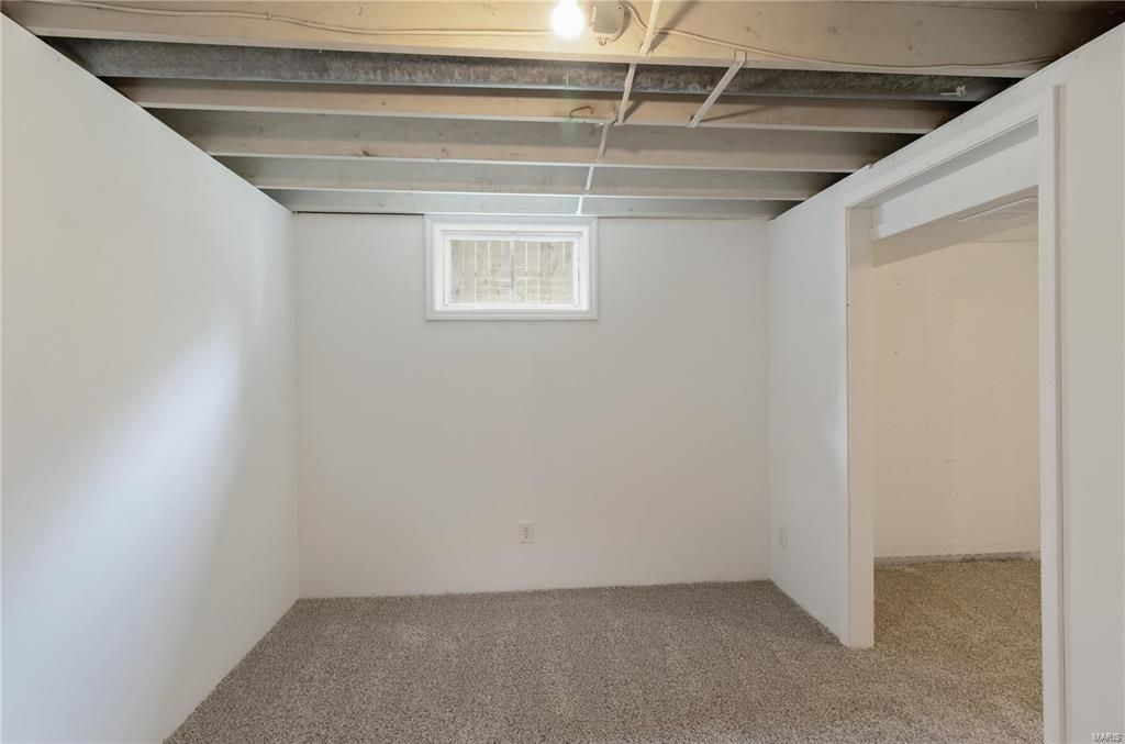 An empty basement with white walls and a window.