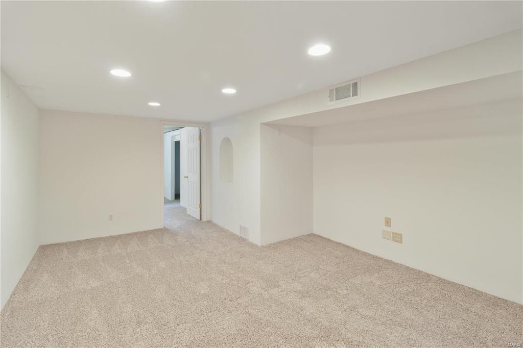 An empty basement with a carpeted floor and white walls.