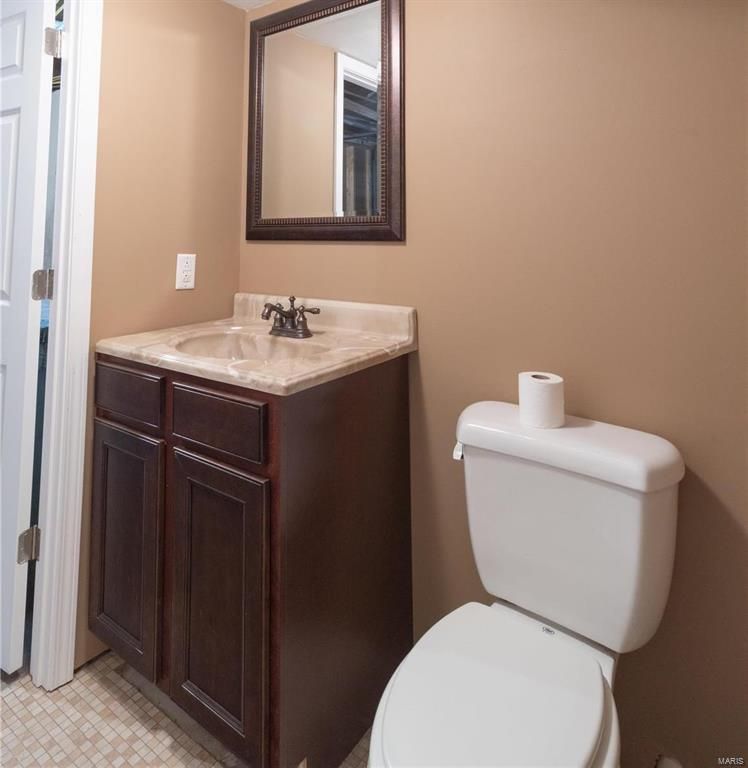 A bathroom with a toilet a sink and a mirror