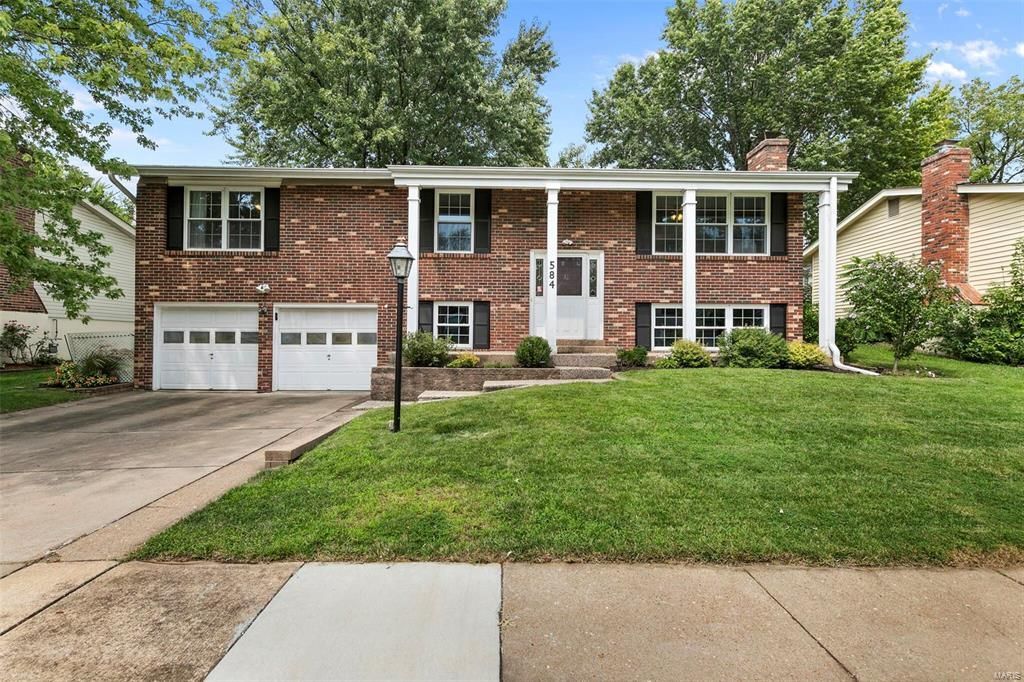 A large brick house with a large lawn in front of it.