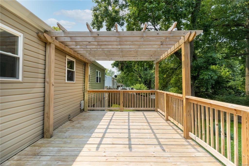 There is a wooden deck with a pergola over it.