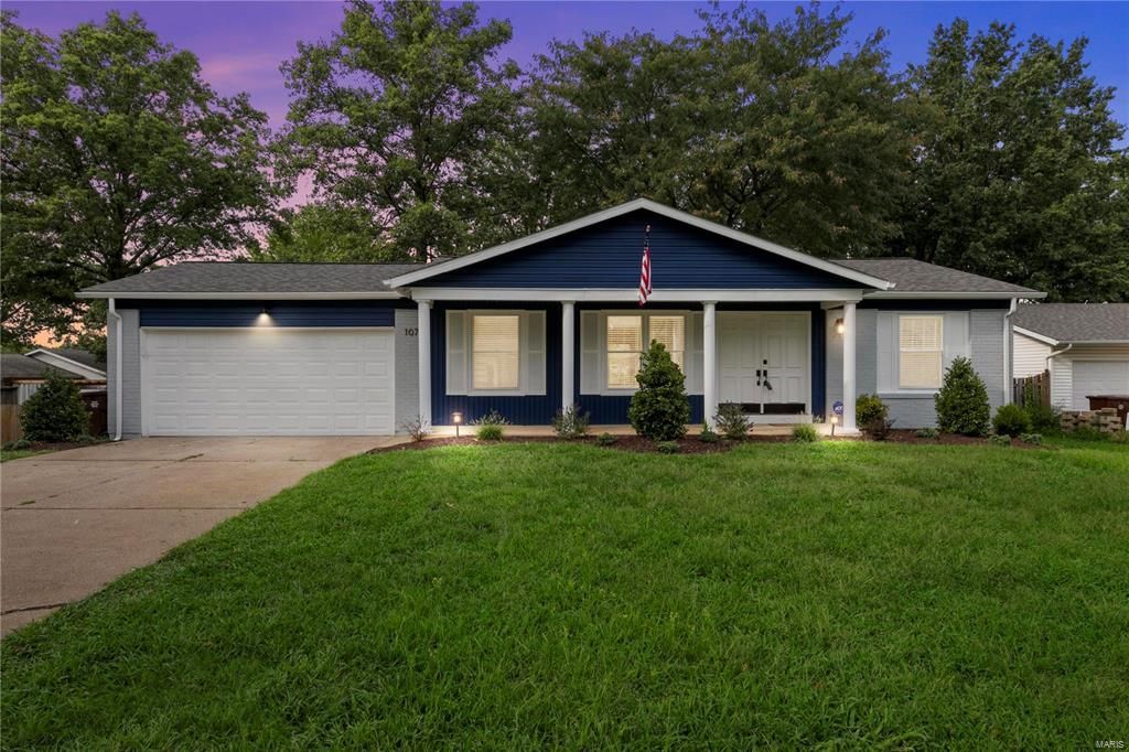 A blue and white house with a large lawn in front of it.
