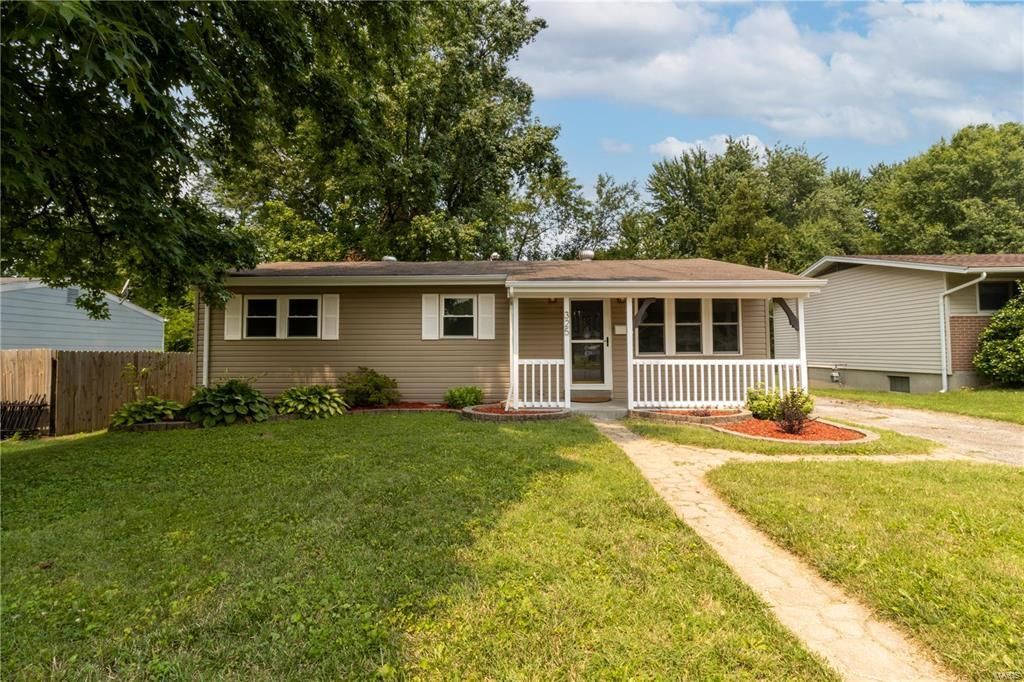 A house with a large lawn and a white porch is for sale.