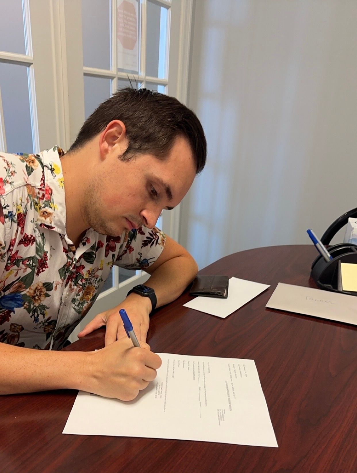A man is sitting at a table writing on a piece of paper