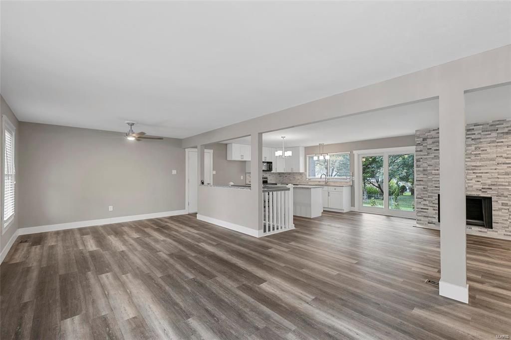 A living room with hardwood floors and a kitchen in the background.