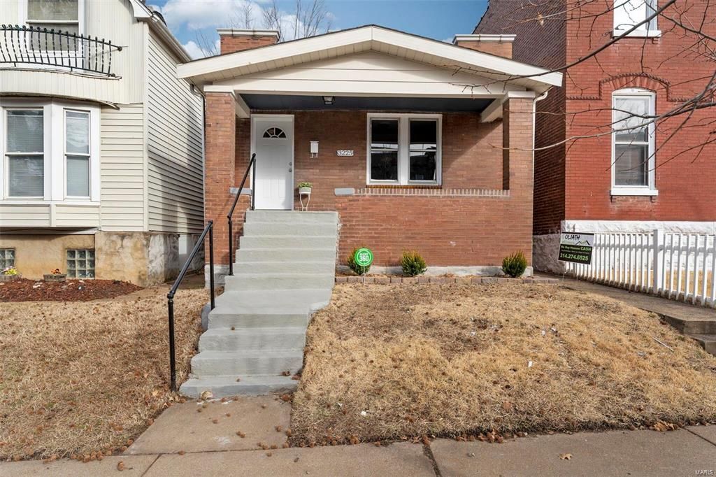 A small brick house with stairs leading up to the front door.