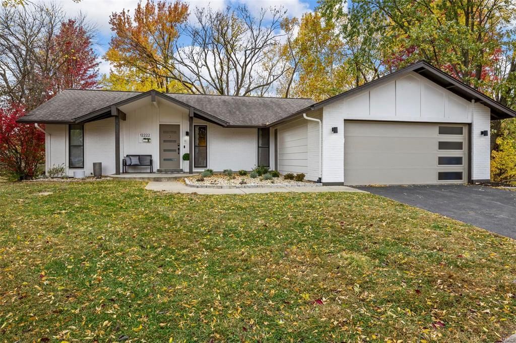 A white house with a garage and a large lawn in front of it.