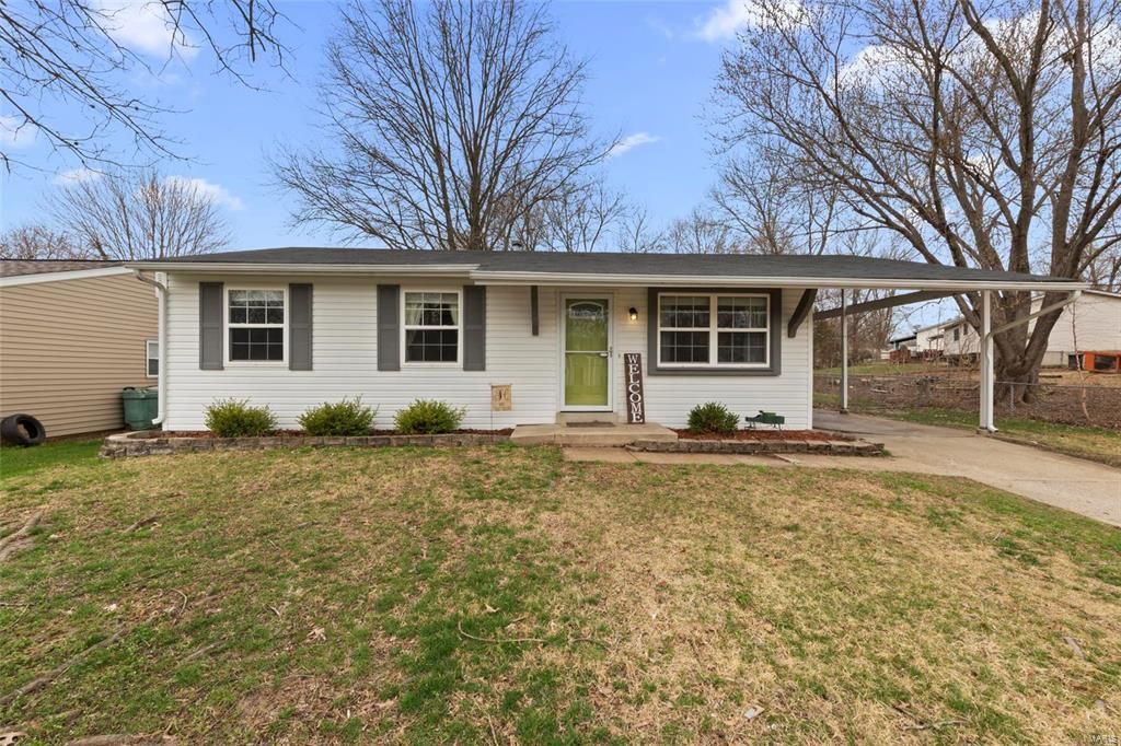 A white house with a green door and shutters is for sale.